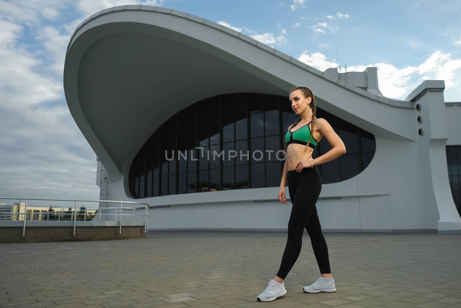 Concept: healthy lifestyle, sport. Attractive happy girl fitness trainer do outdoor workout at modern downtown urban area during sunset.