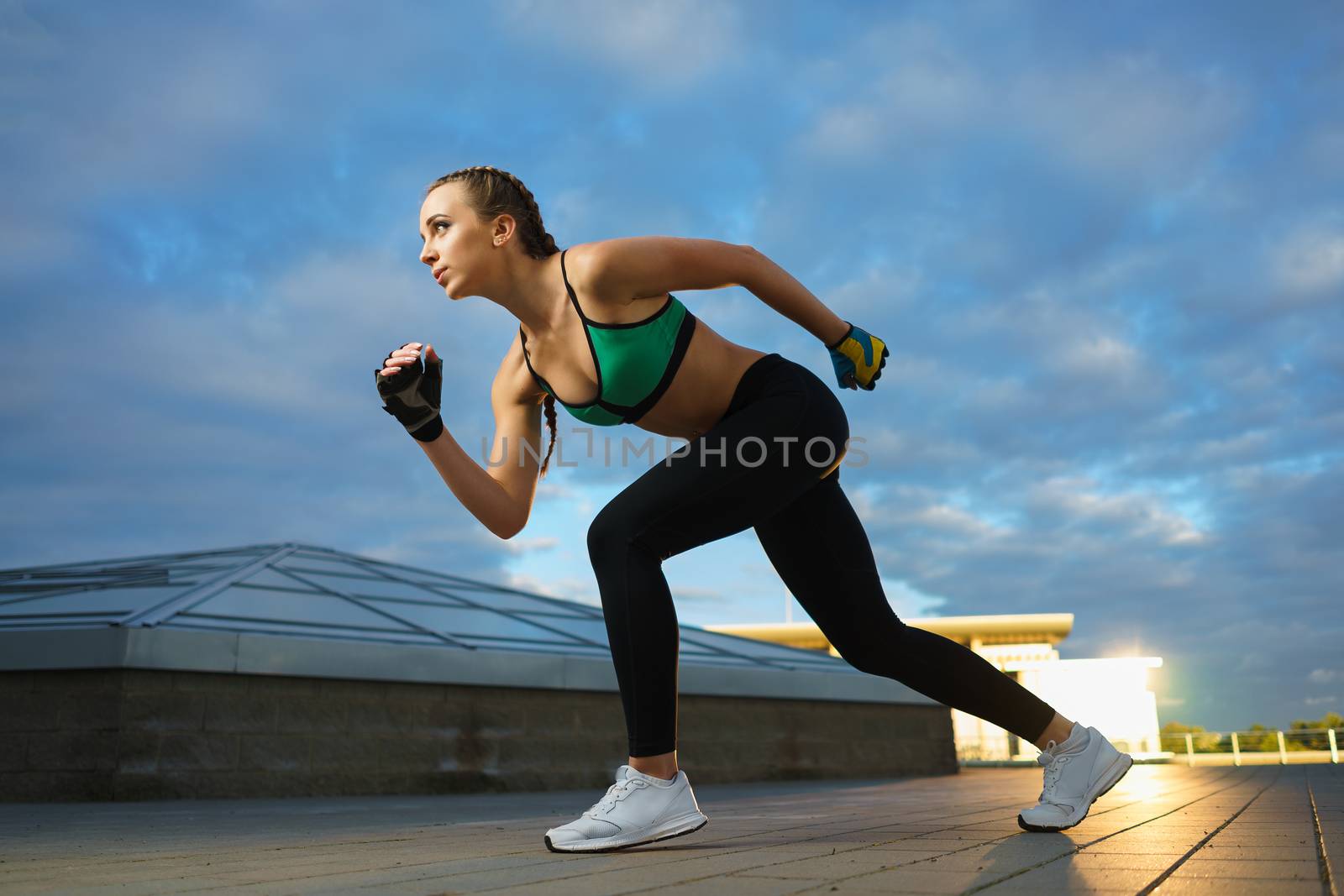 Concept: healthy lifestyle, sport. Attractive happy girl fitness trainer run outdoor workout at modern downtown urban area during sunset.