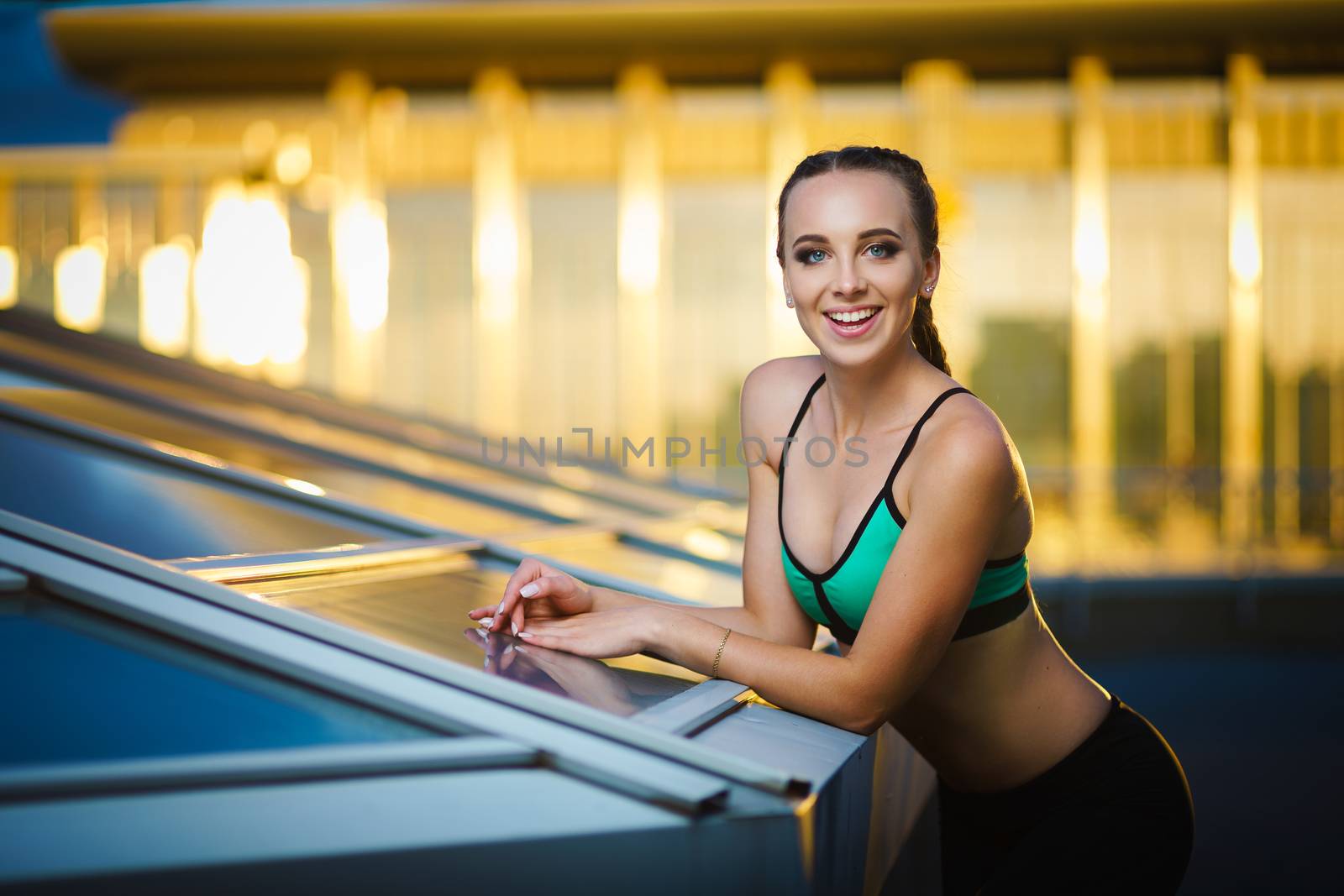 Concept: healthy lifestyle, sport. Attractive happy girl fitness trainer do outdoor workout at modern downtown urban area during sunset.