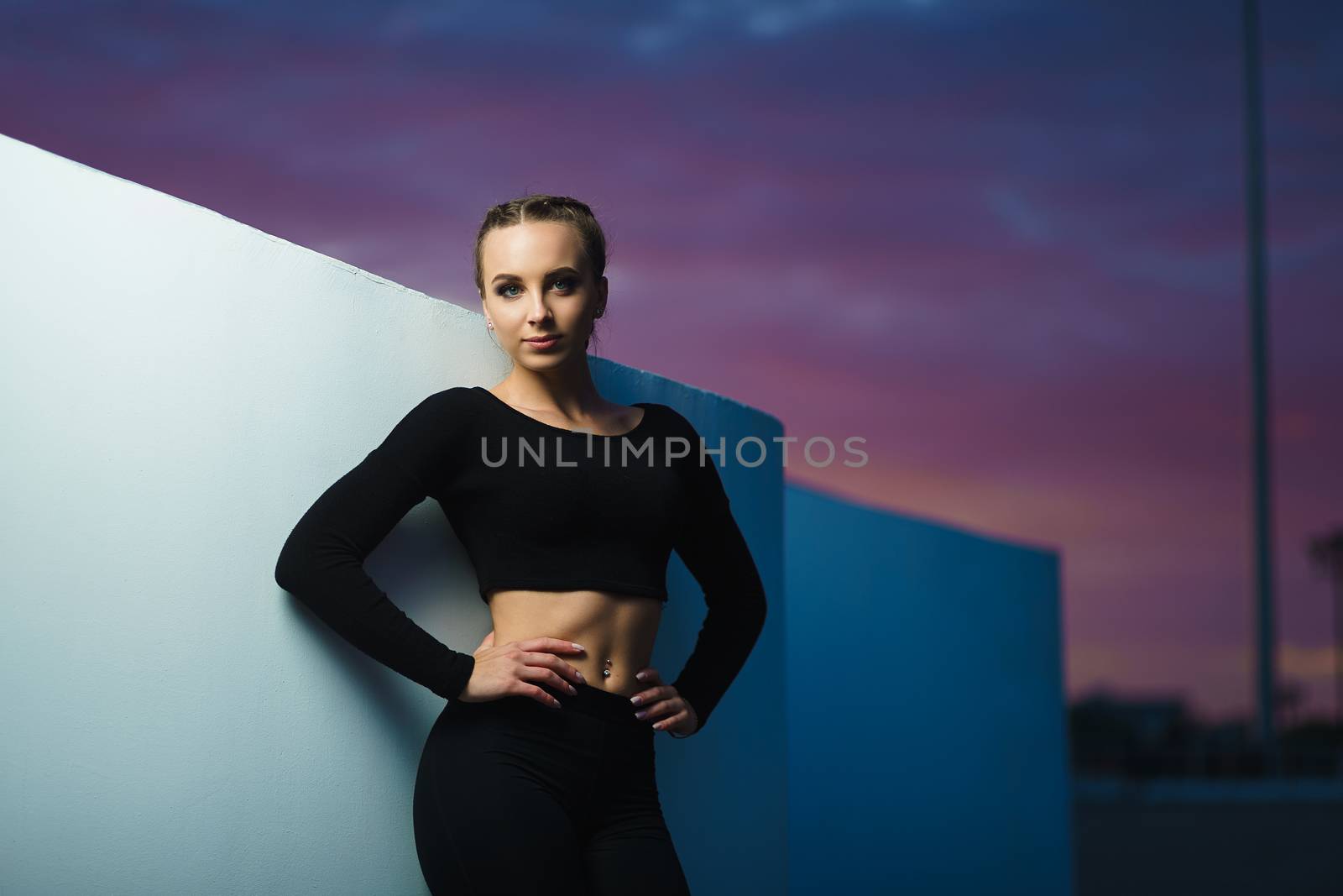 Attractive fitness girl do workout at modern urban area sunset by mrakor