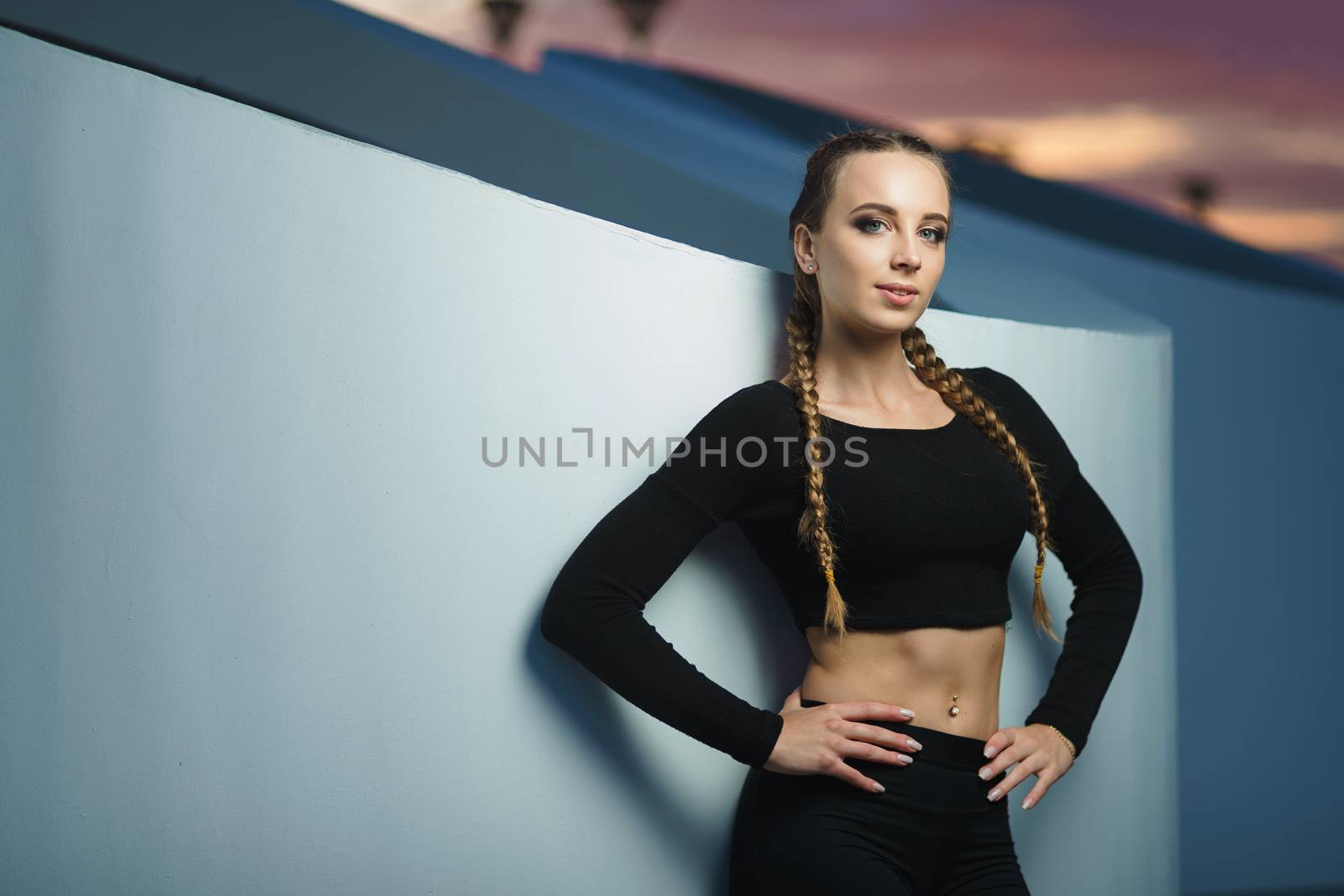 Attractive fitness girl do workout at modern urban area sunset by mrakor