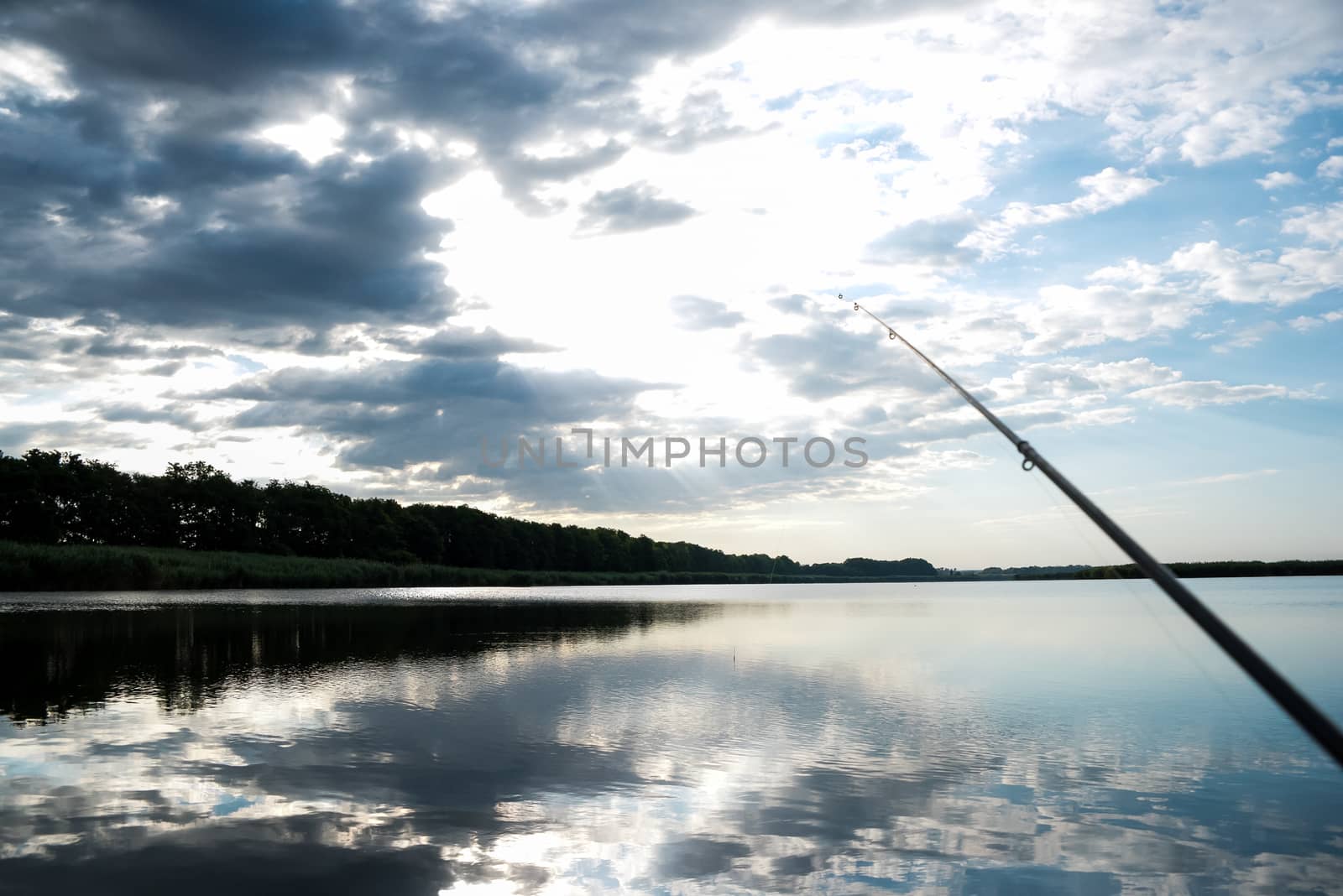 Fisherman sport hobby fishing rod or spinning reel on the river. Fishing on sunrise. beautiful sunrise on the river is reflected in water.