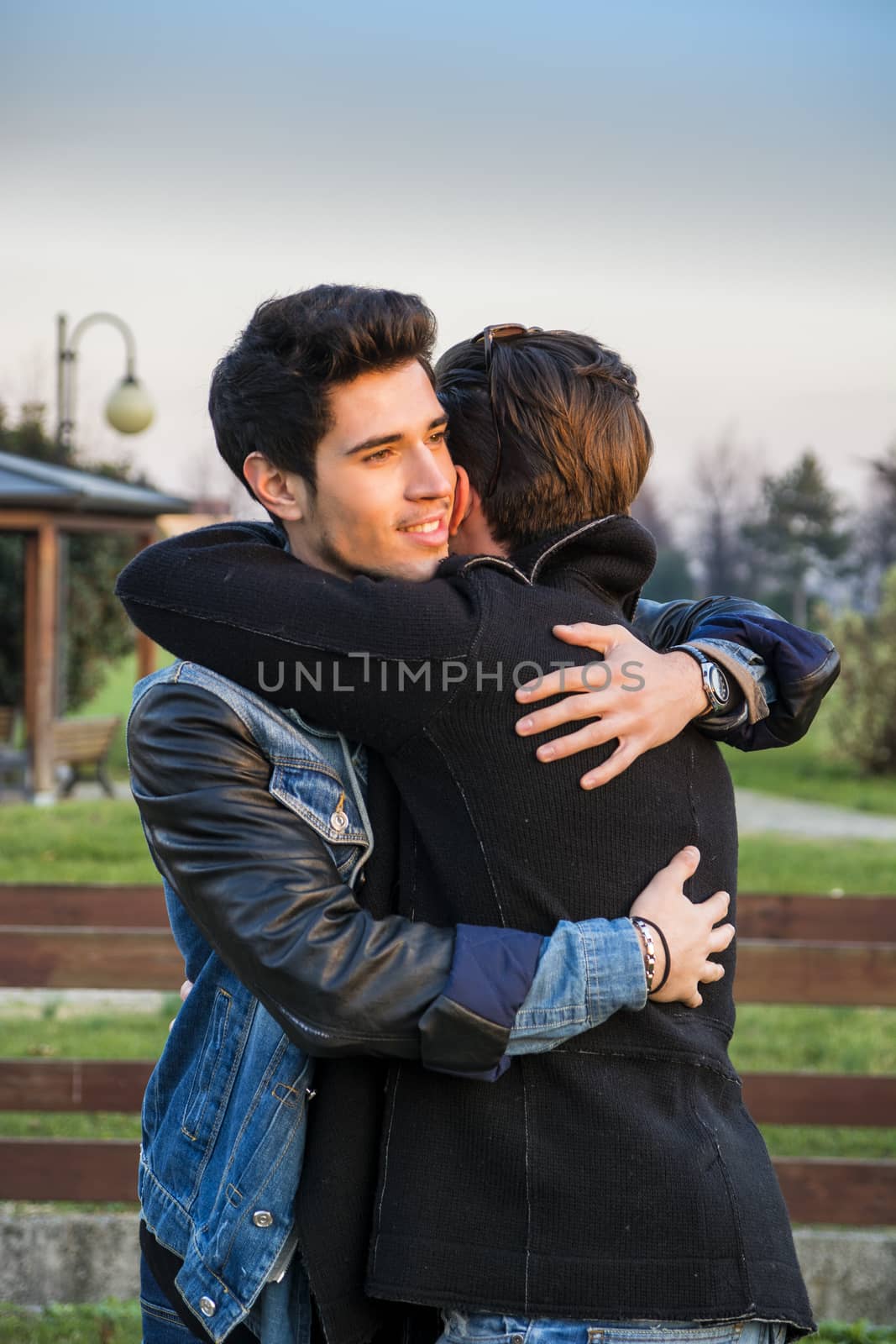 Portrait of cheerful and handsome man hugging his best friend and looking away outdoor