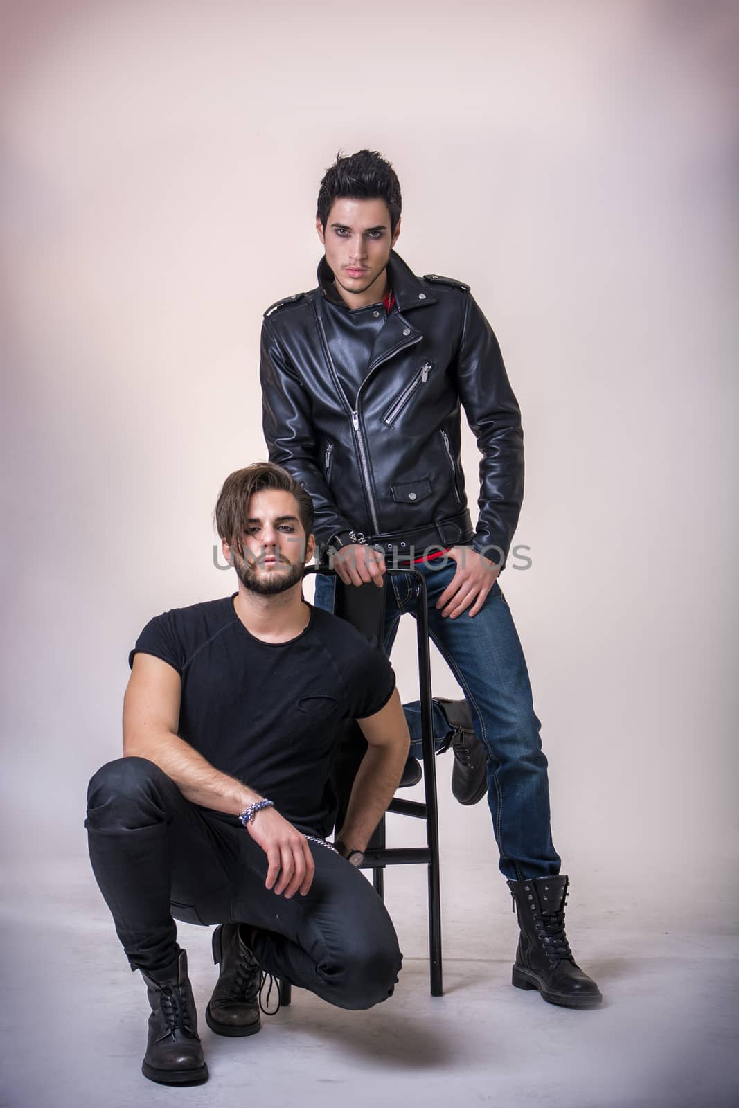 Two attractive young hard rock men posing in studio. White background