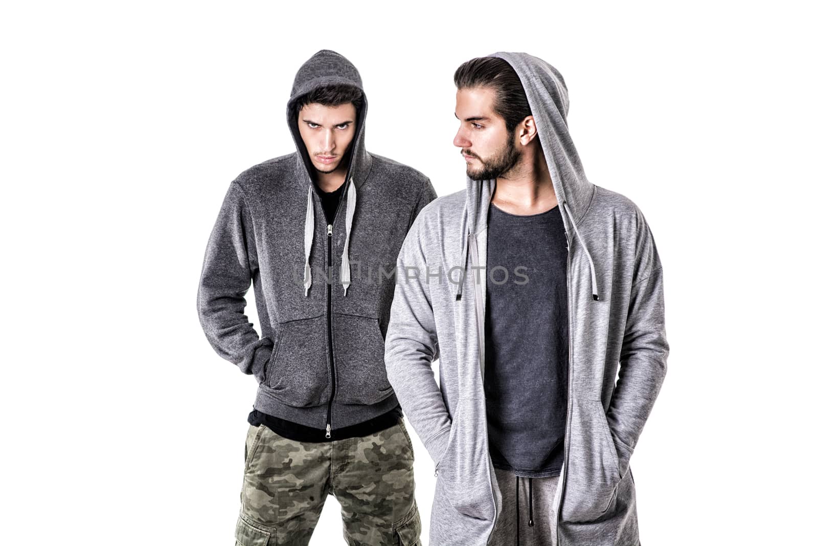 Two young men wearing military and sport clothes. Wearing hoods on heads. Studio shot.