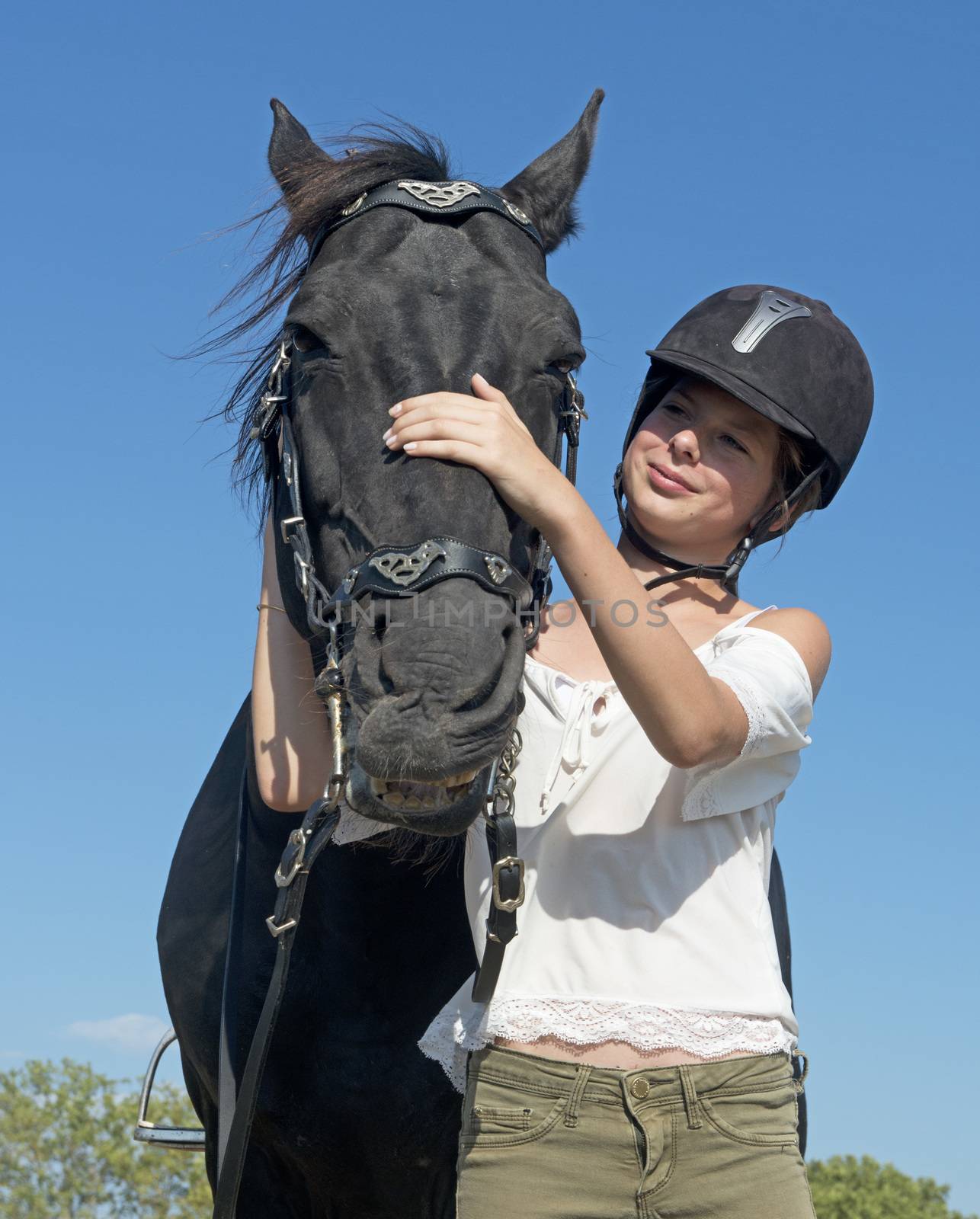 young girl riding a black stallion in a field