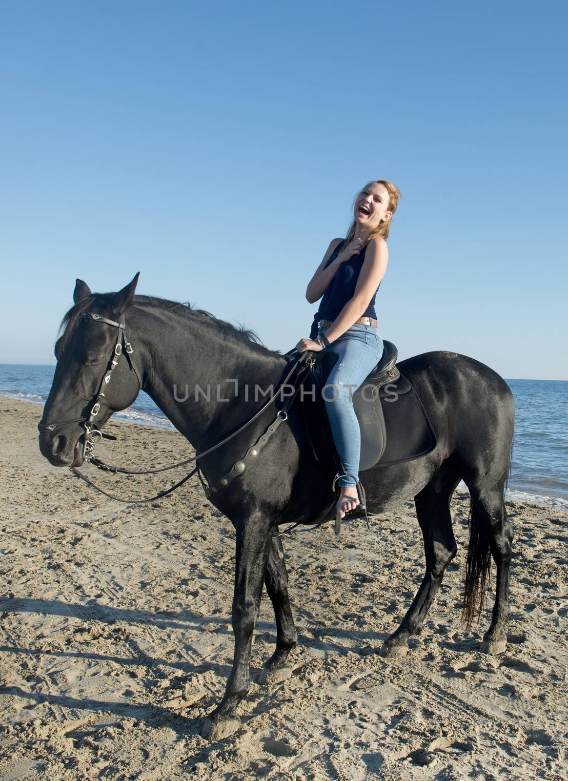 laughing woman and black horse on the beach