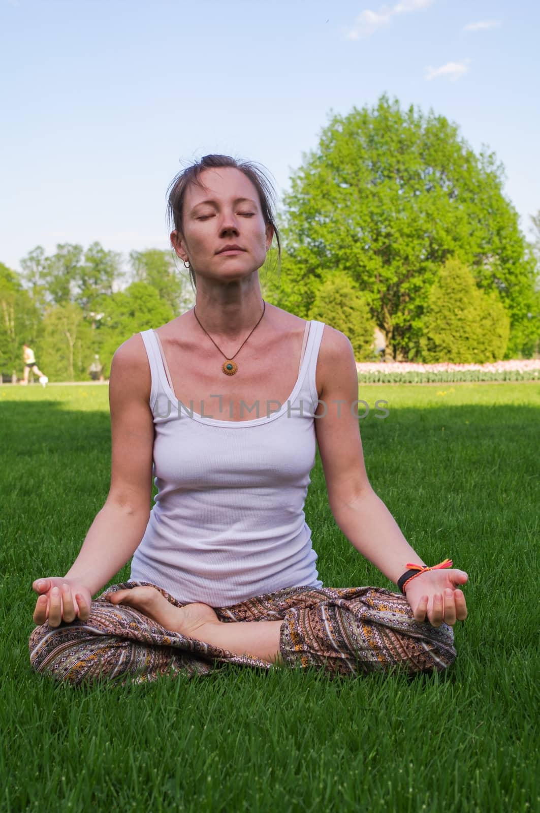Young woman sitting in yoga pose meditation outdoors by evolutionnow