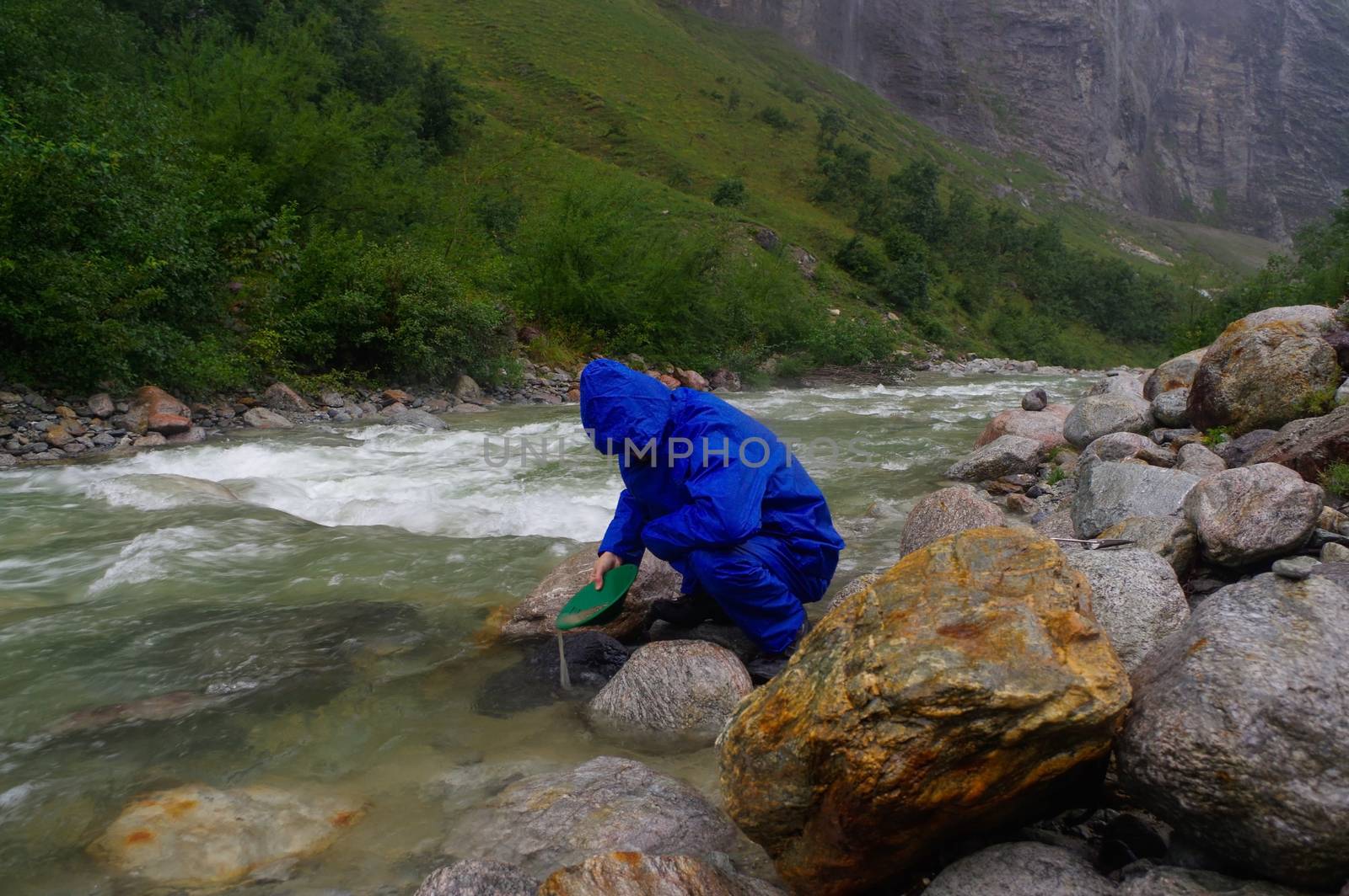 man prospector panning gold on a river with sluice box  rainy da by evolutionnow