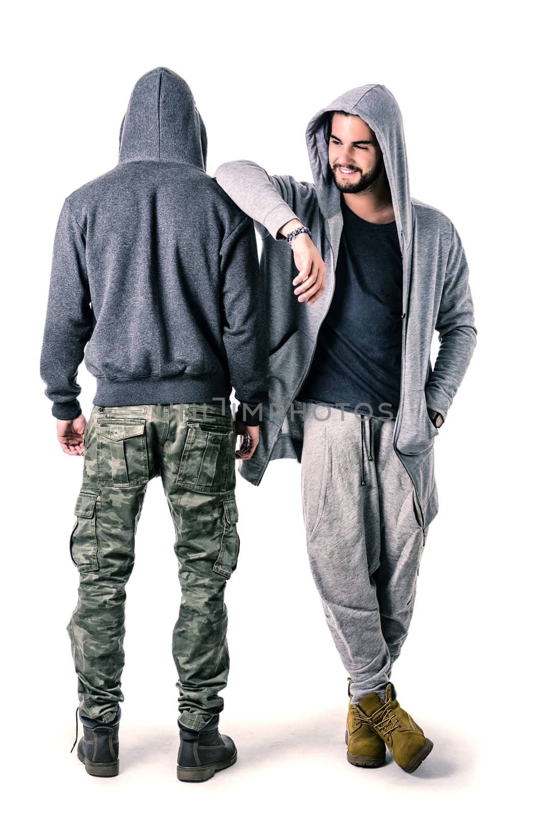Two young men wearing military and sport clothes. Wearing hoods on heads. Studio shot.