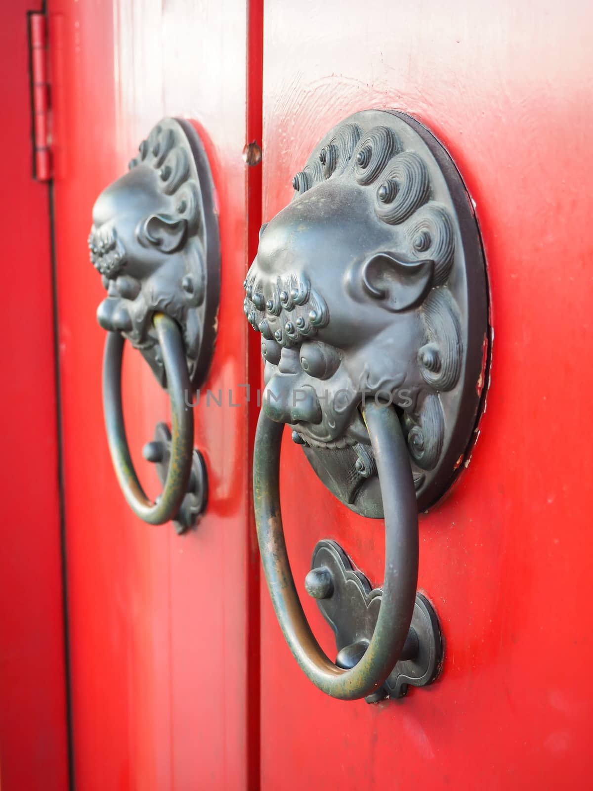 Old brass knocker with lion head in the traditional Chinese style on the temple door by worrayuth