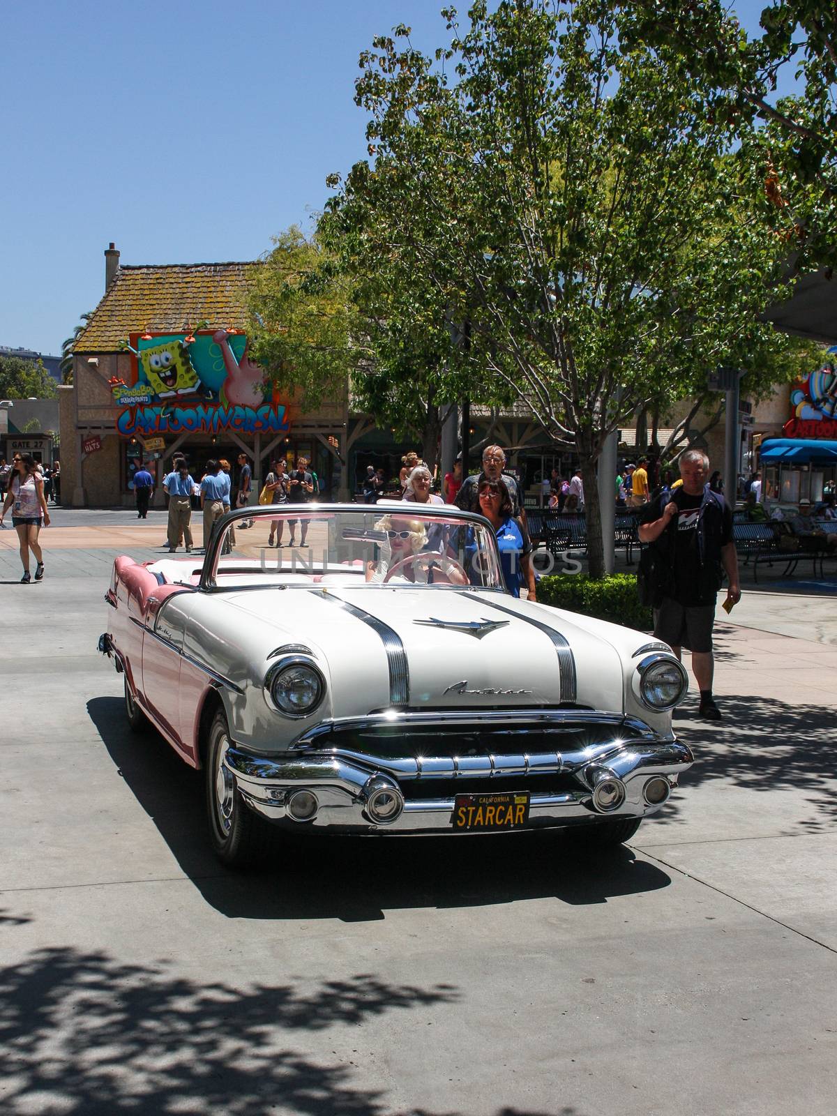 Los Angeles, CA, United States - 15 June 2010. Model in an image of Marilyn Monroe drives through the streets of Universal Studios in Los Angeles Hollywood . Beige Pontiac in retro style perfectly with her dress, hair and glasses.