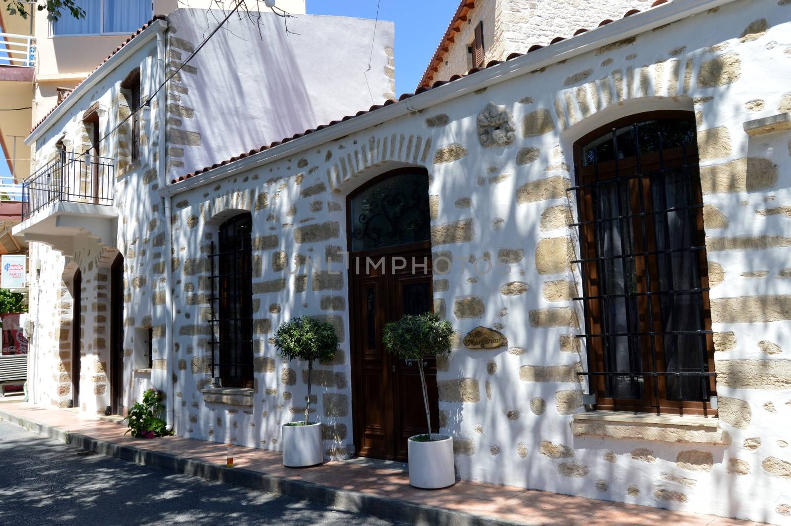 White facade with doors and wooden windows with trees green.