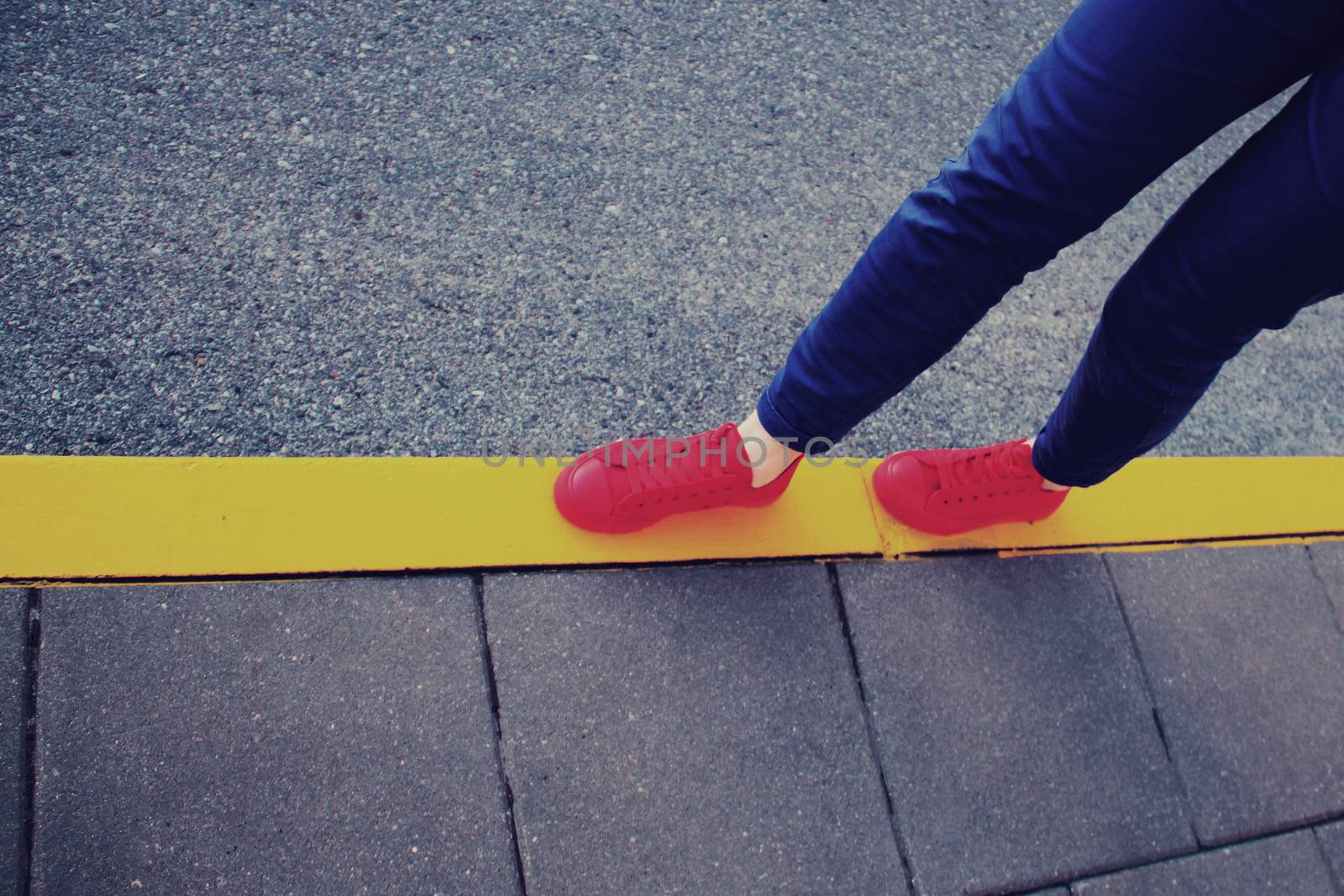 Red sneakers on yellow road line by Voinakh