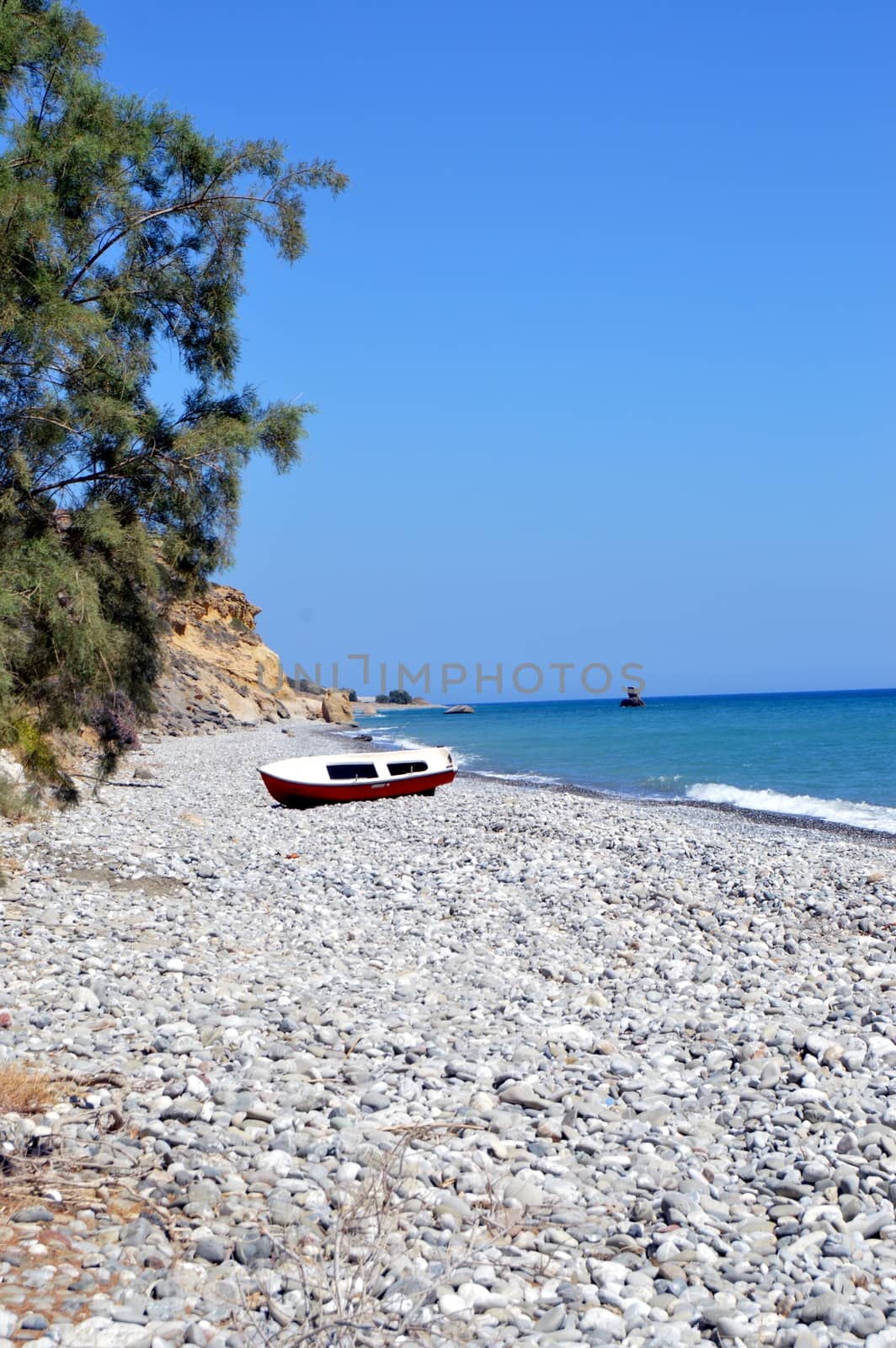 A fine sand beach with a hill, a blue sky and waves.