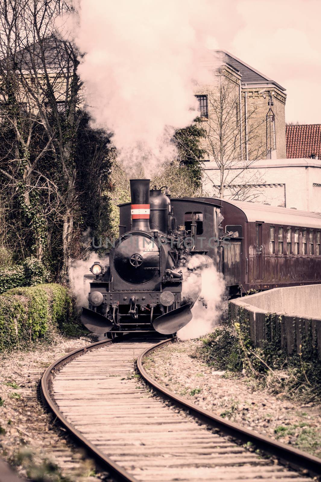 Steamy veteran train driving on a railway in the city