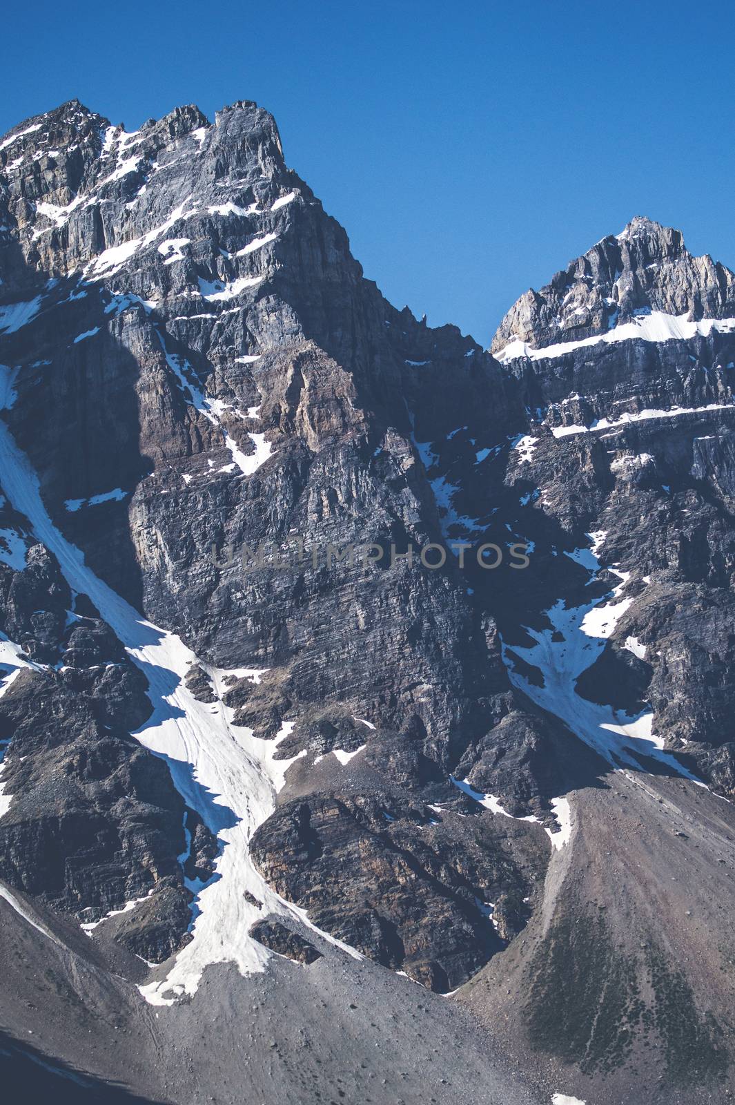 Rough mountain with cliffs and snow in blue sky