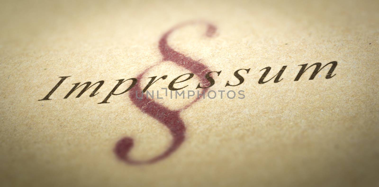 Word Impressum printed on a paper texture with blur effect and silcrow symbol