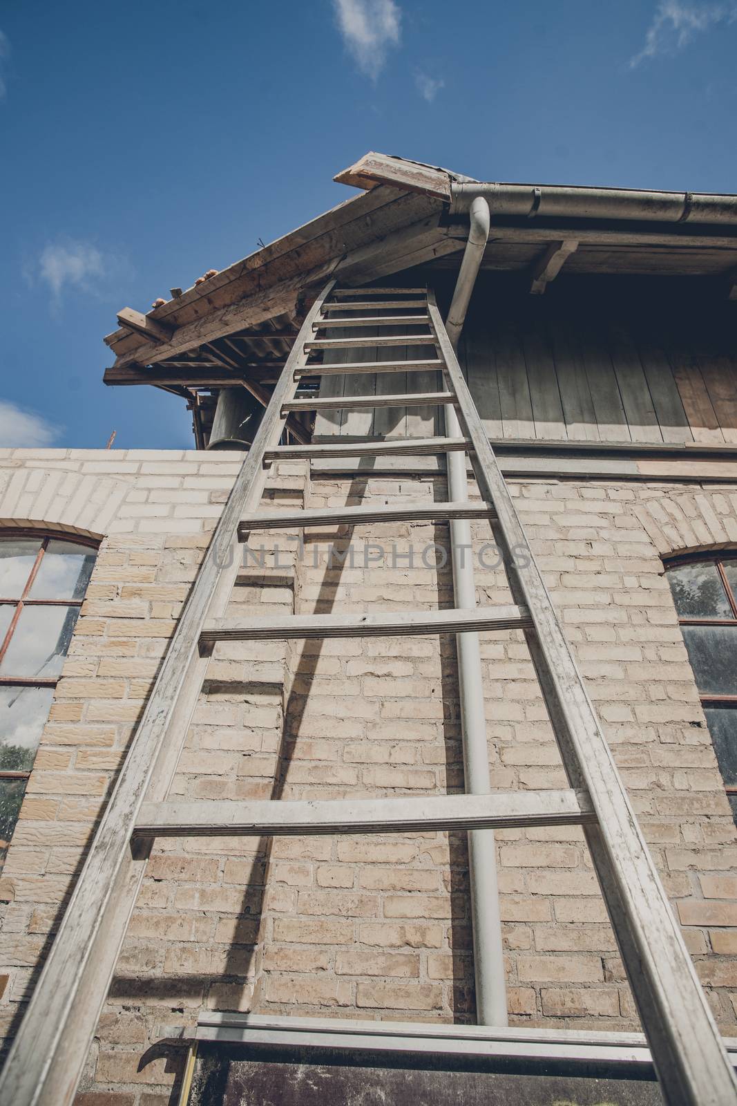 Tall ladder at an old building with damaged roof
