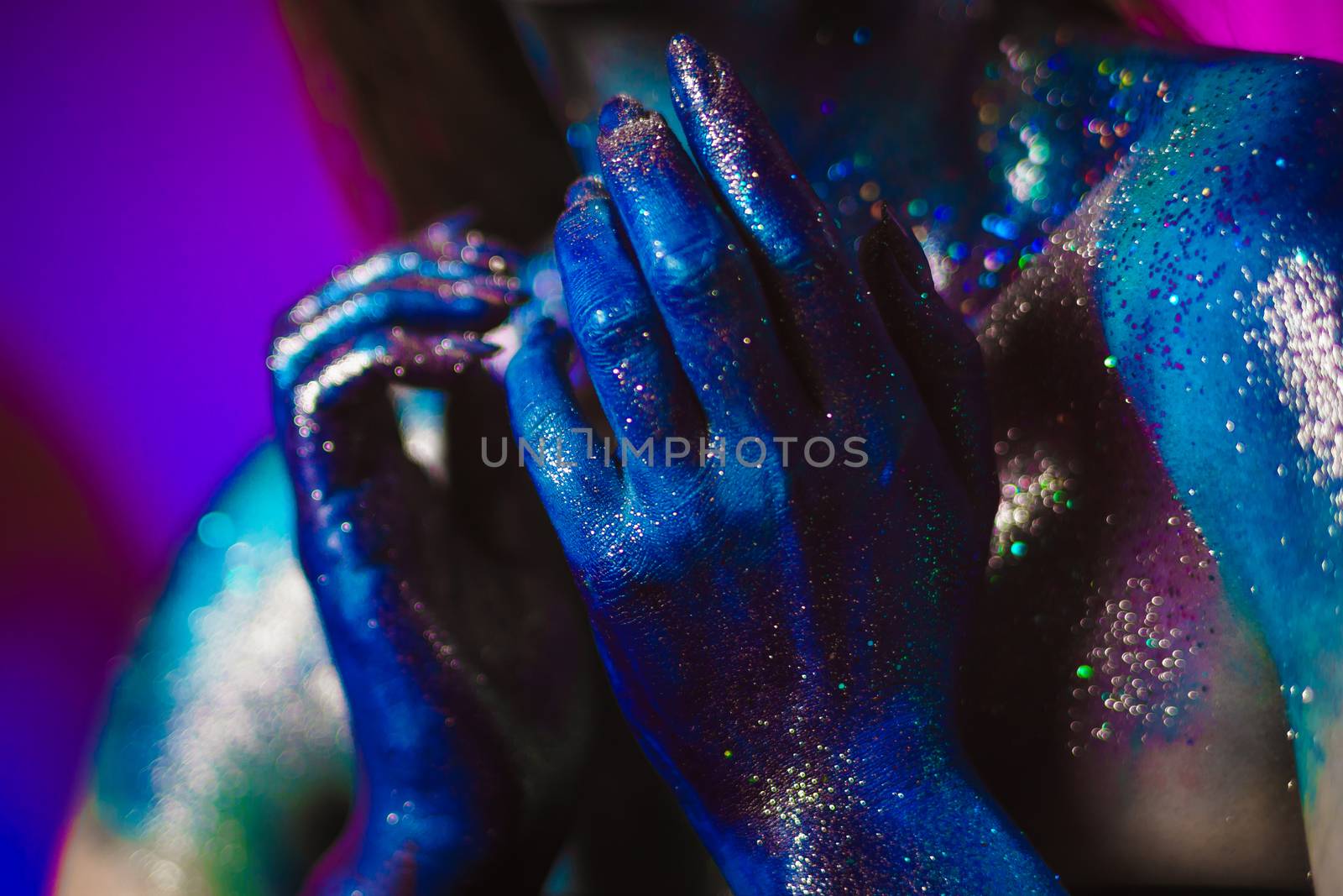 Portrait of an beautiful woman painted with purple cosmic colors and spangled. Body art project. Concept: fashion, makeup, extraordinary.