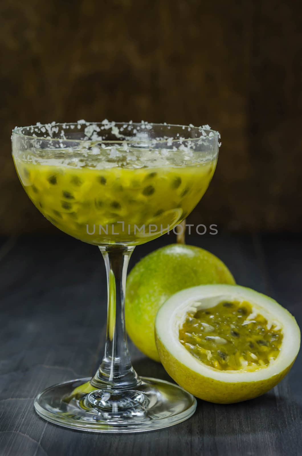 Fresh passion fruit juice in glass with passion fruits over wooden background , still life