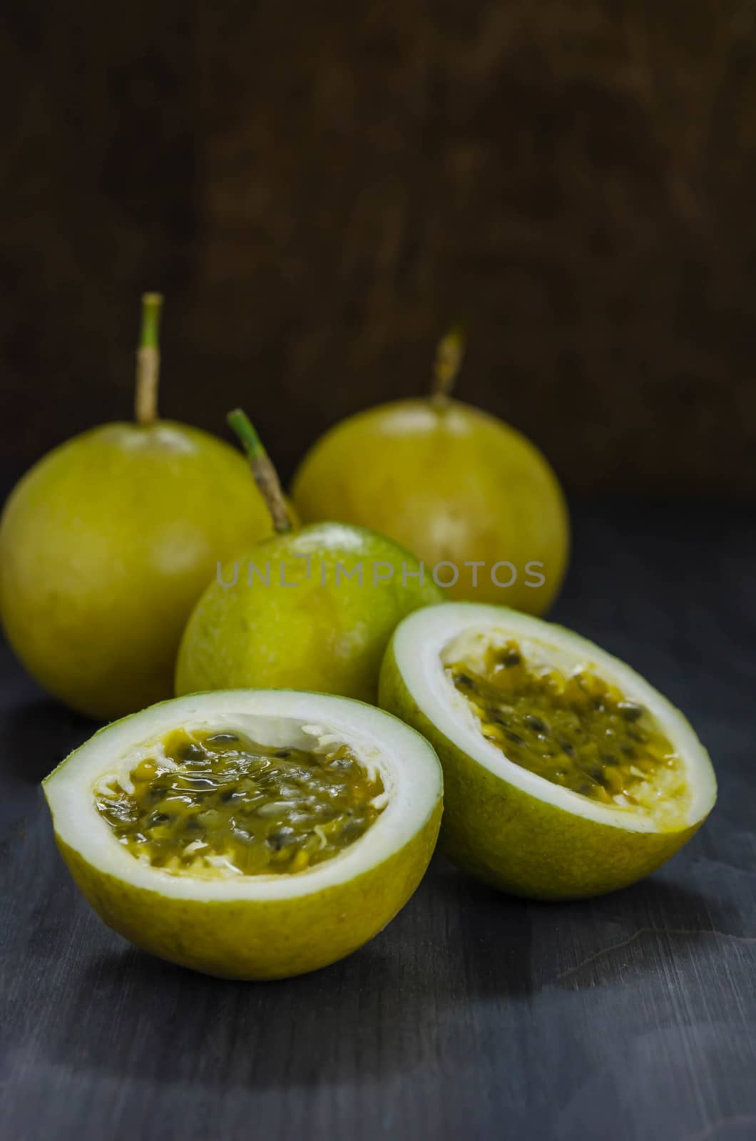 Fresh passion fruit juice in glass with passion fruits over wooden background , still life