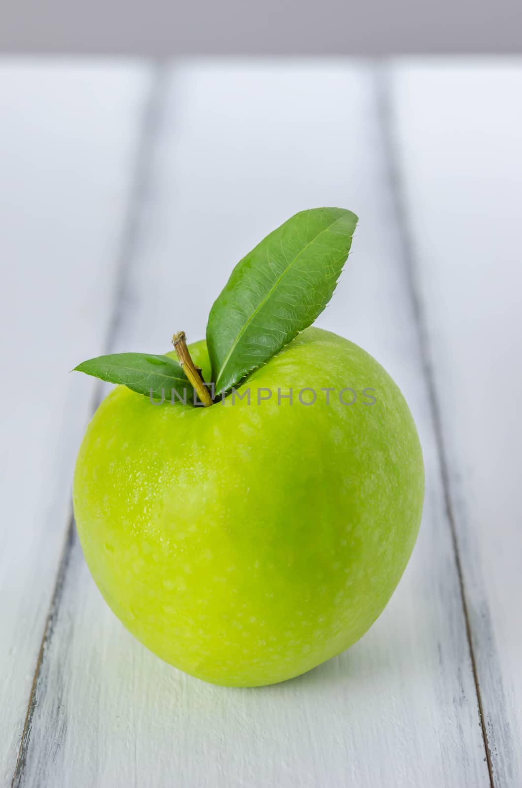 Ripe green apple with leaf  on a wooden background