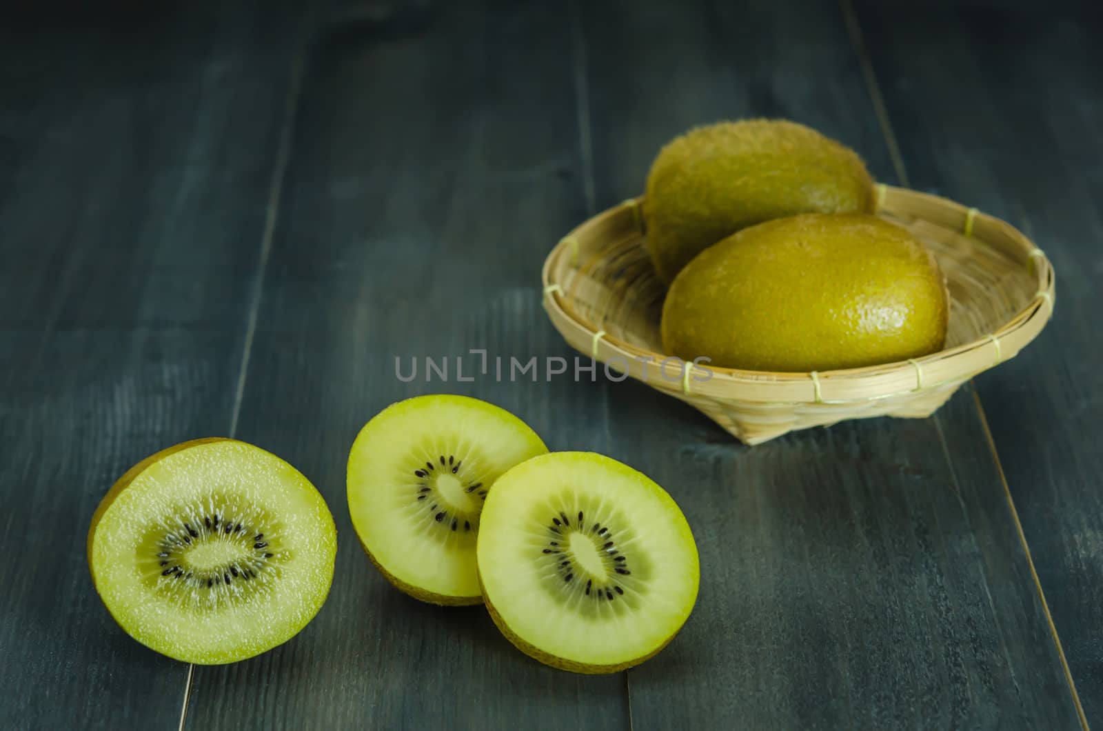 kiwi fruit and sliced with bamboo basket on wooden background , still life