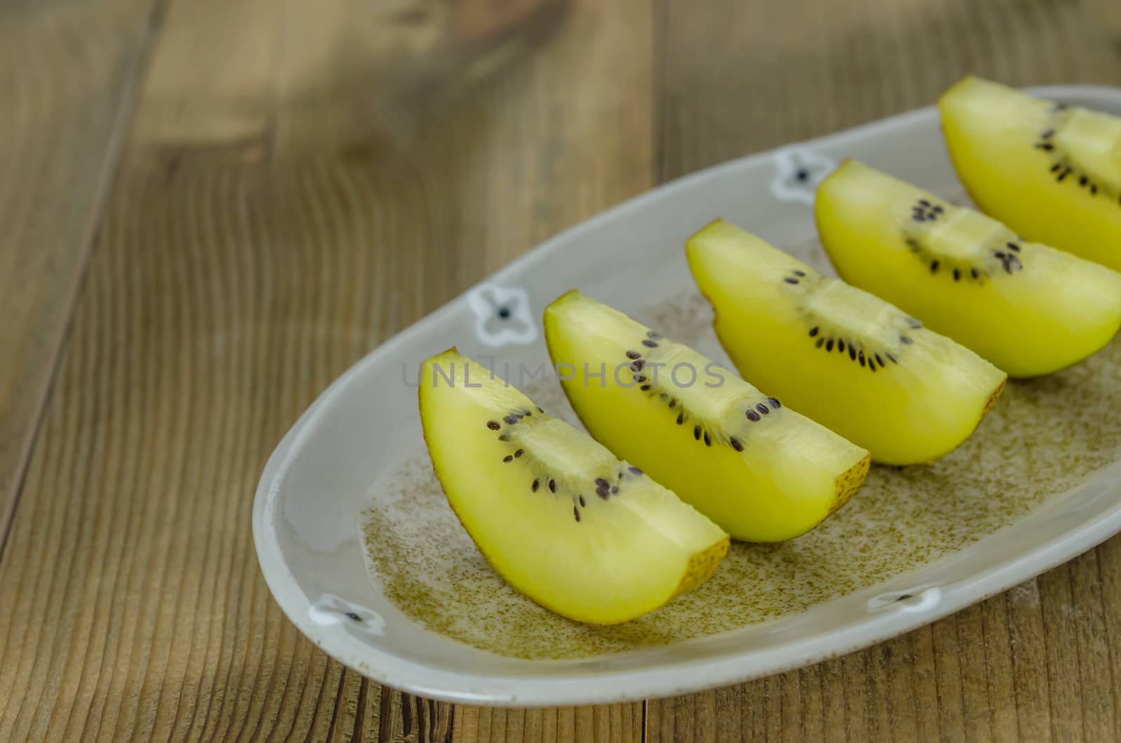 sliced of golden kiwi fruit  on dish over wooden background