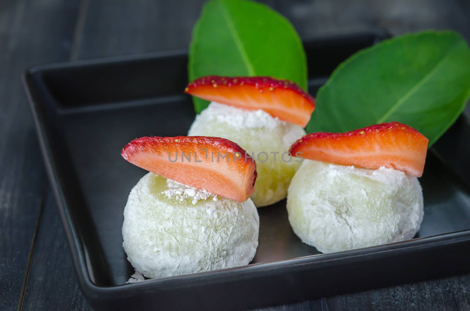 Strawberry Daifuku Mochi Japanese dessert on black dish over wooden background