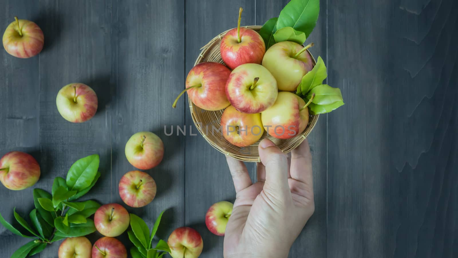 human hand holding red and yellow apple  on wooden background , Top view