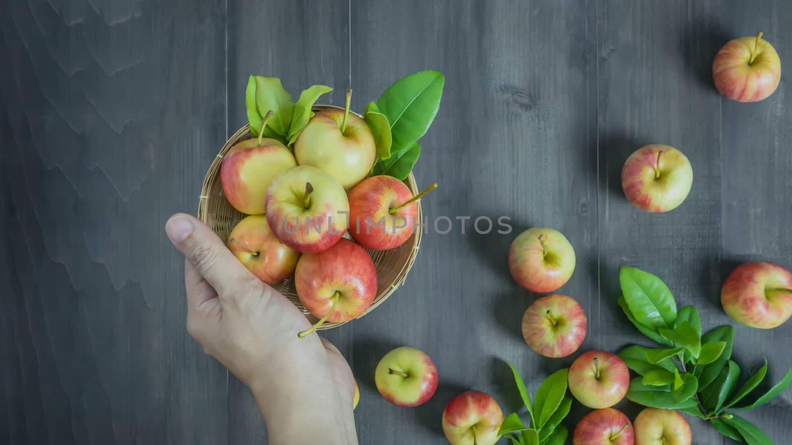 human hand holding red and yellow apple  on wooden background , Top view