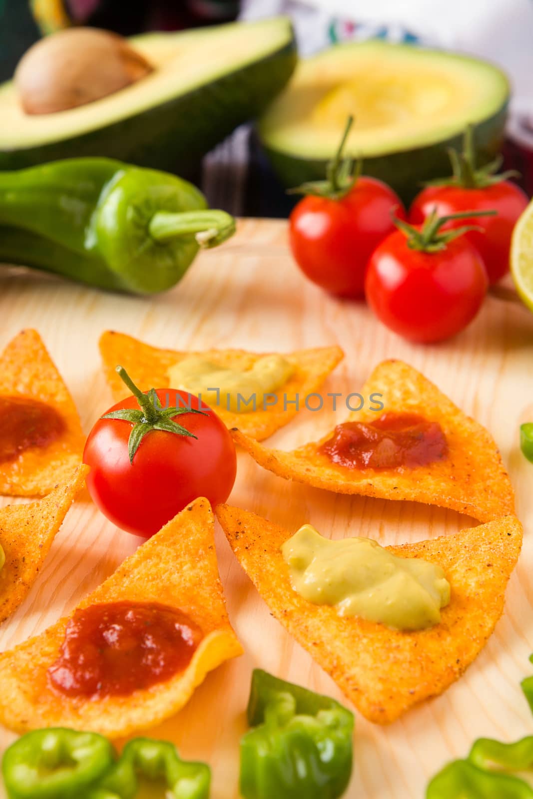 Close up of nachos chips tomato pepper and avocado over a chopping board