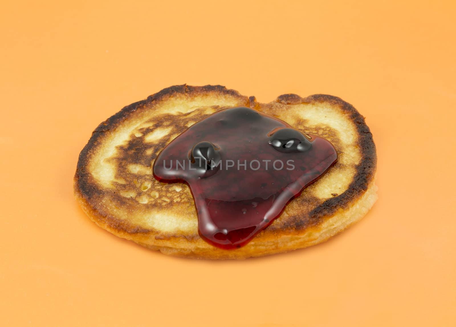 Closeup of lush pancakes with jam on a yellow background