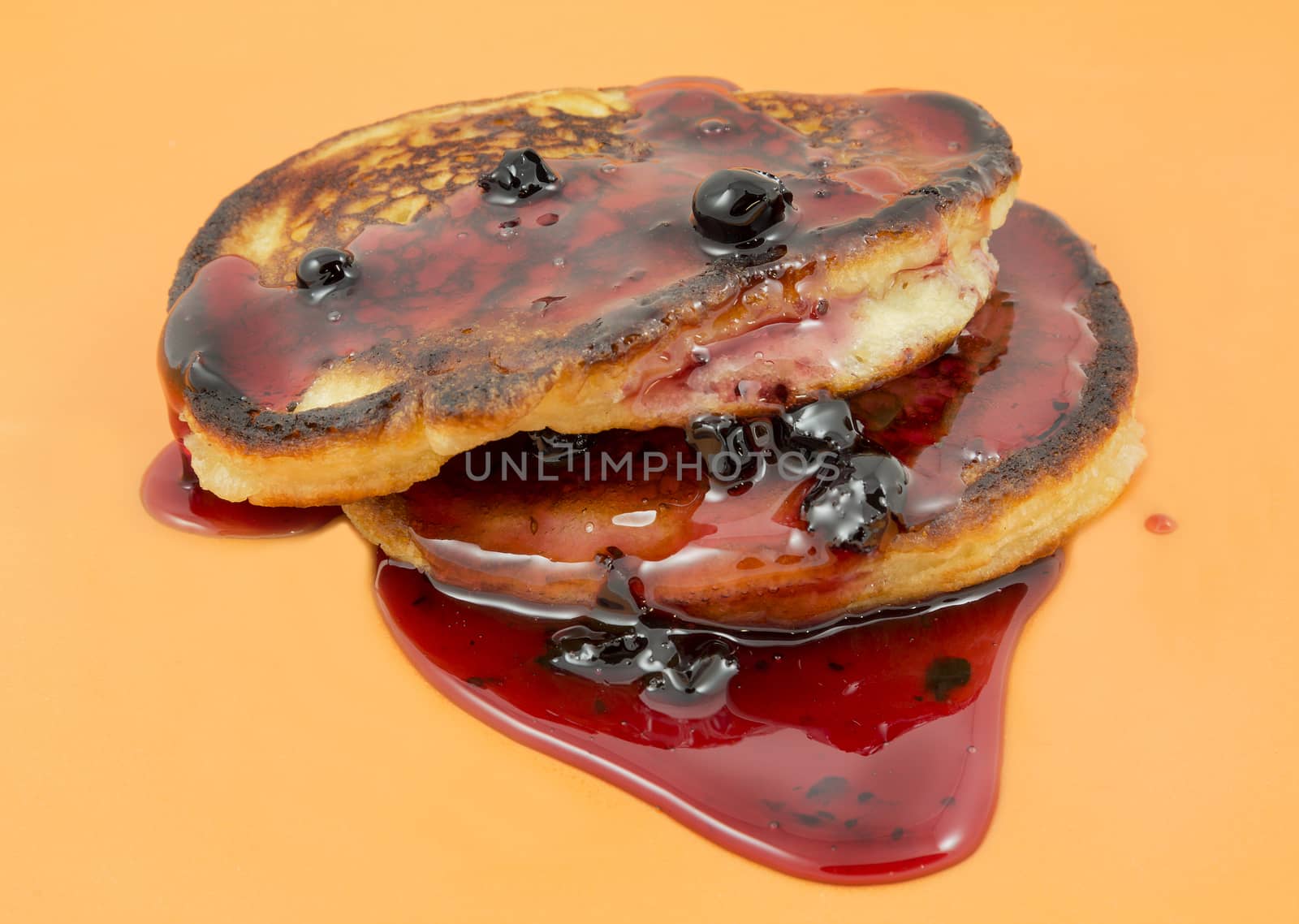 Closeup delicious puffy pancakes with jam on a yellow background