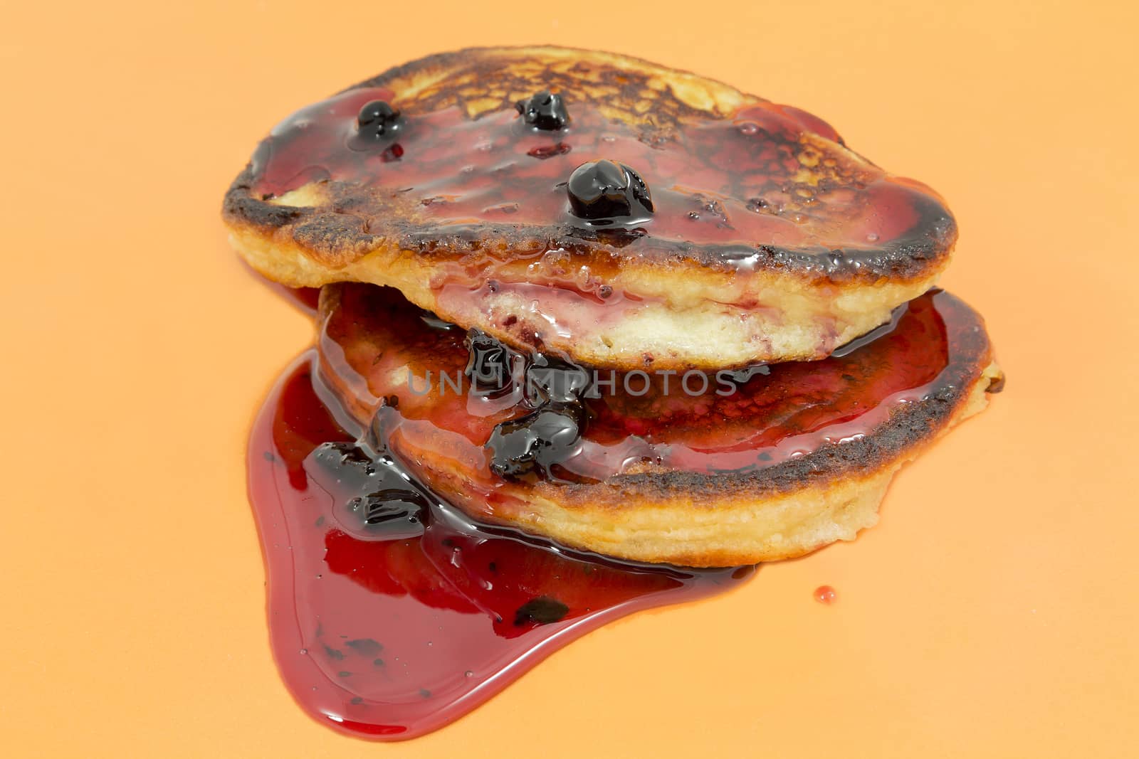 Closeup delicious puffy pancakes with jam on a yellow background