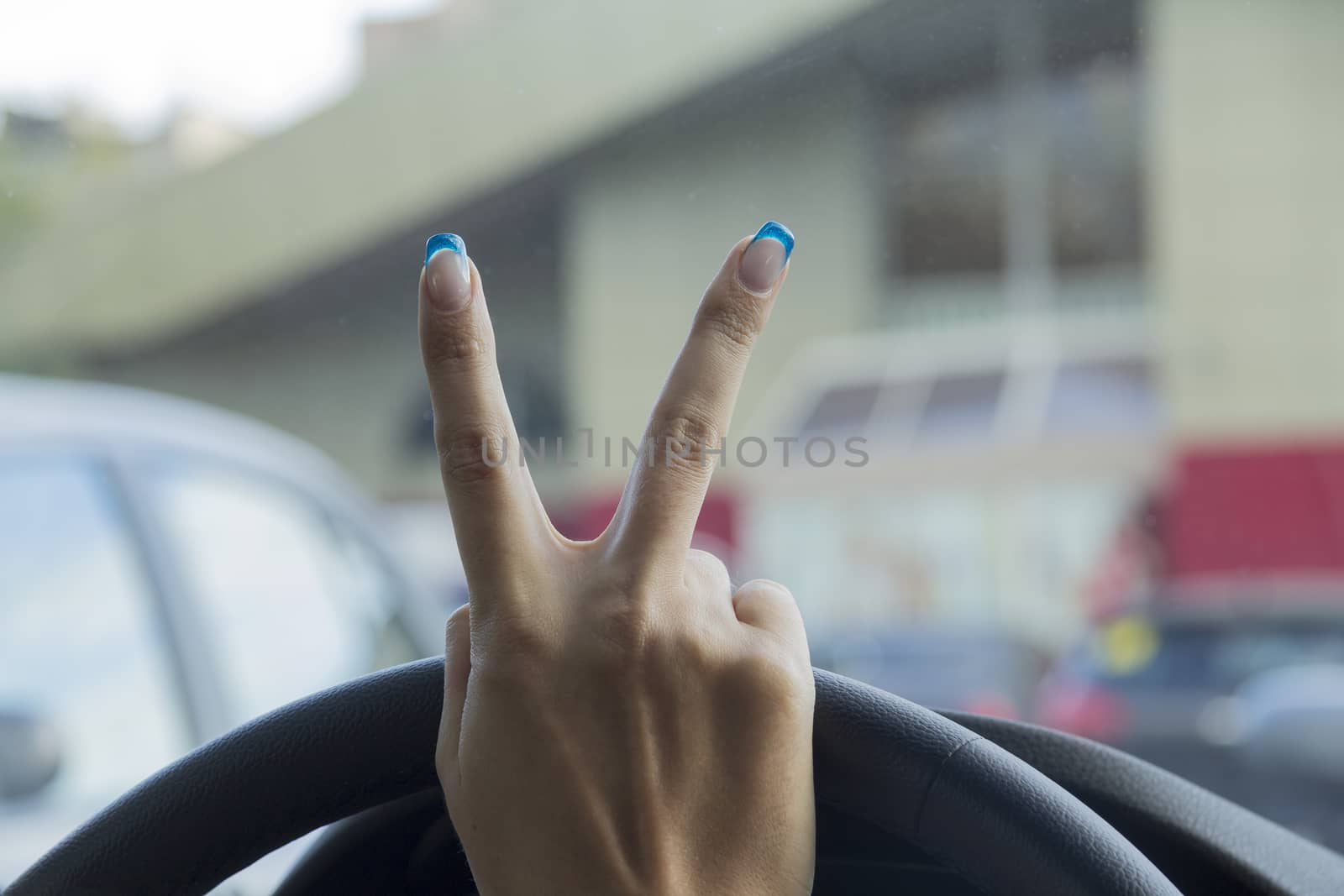 Girl's hand with two fingers up in a symbol of peace or victory in the car