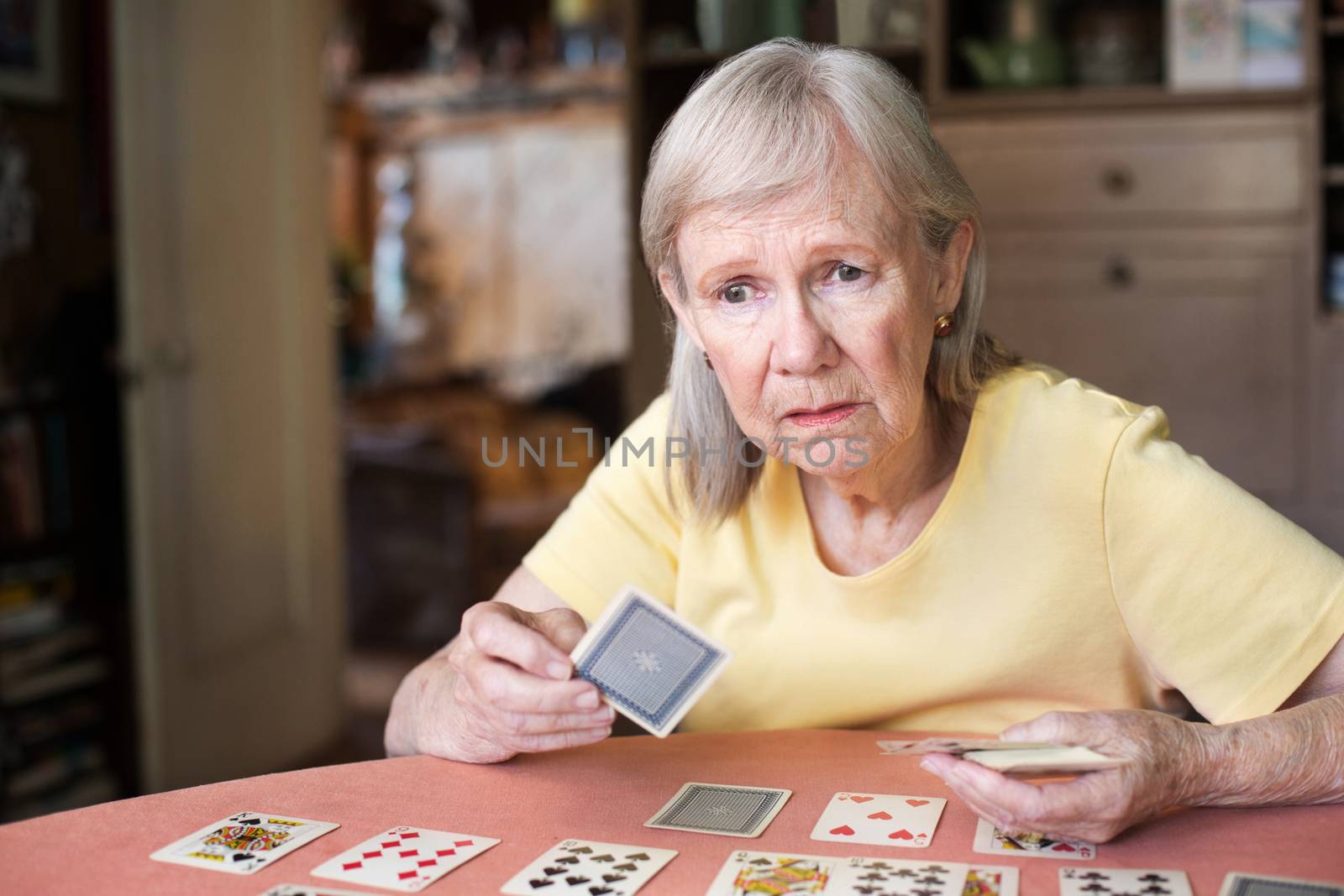 Worried woman playing cards at table by Creatista