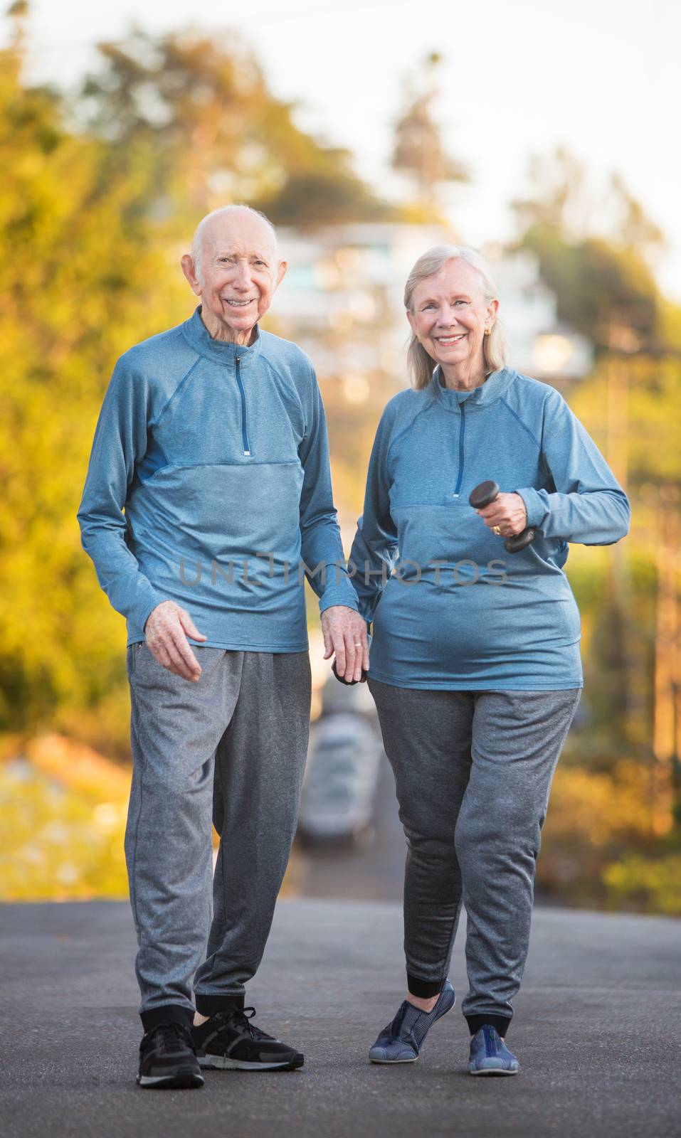 Happy male and female mature couple walking along street with steep hill