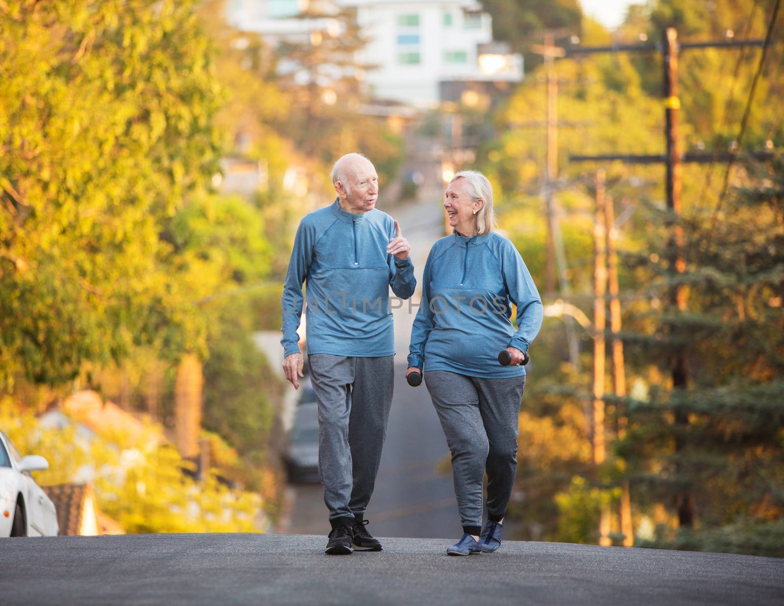 Senior couple walking along street on hill by Creatista