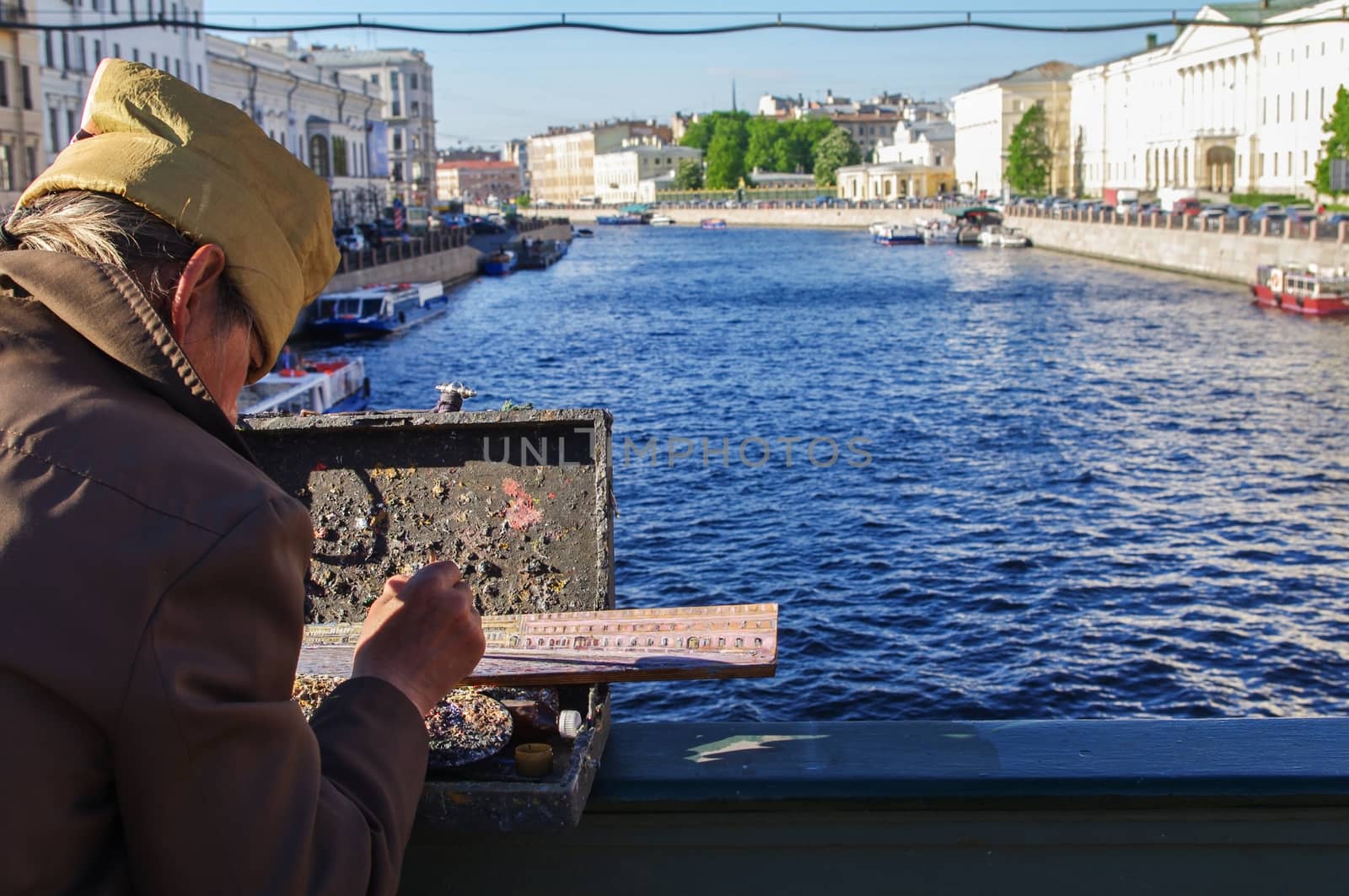 St. Petersburg, Russia - May 22, 2014: a street artist paints river landscape on the bridge over the Neva River.