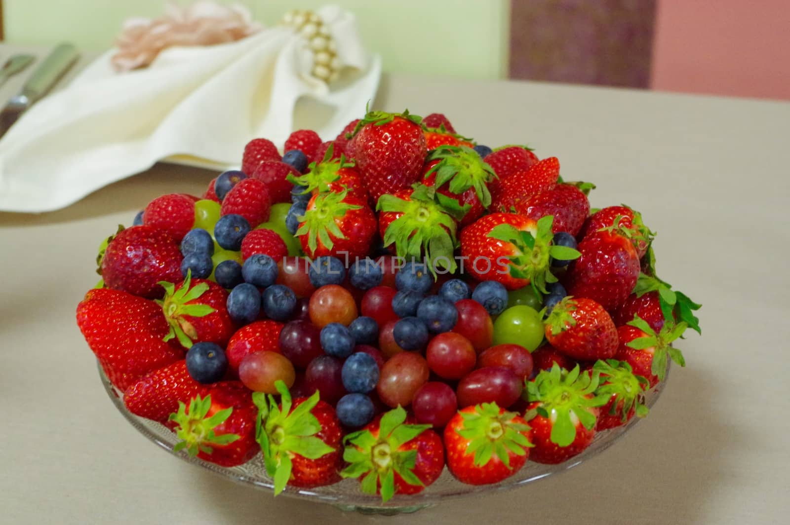 Fresh berries, blueberry, strawberry, raspberry in a glas bowl plate on gray table by evolutionnow