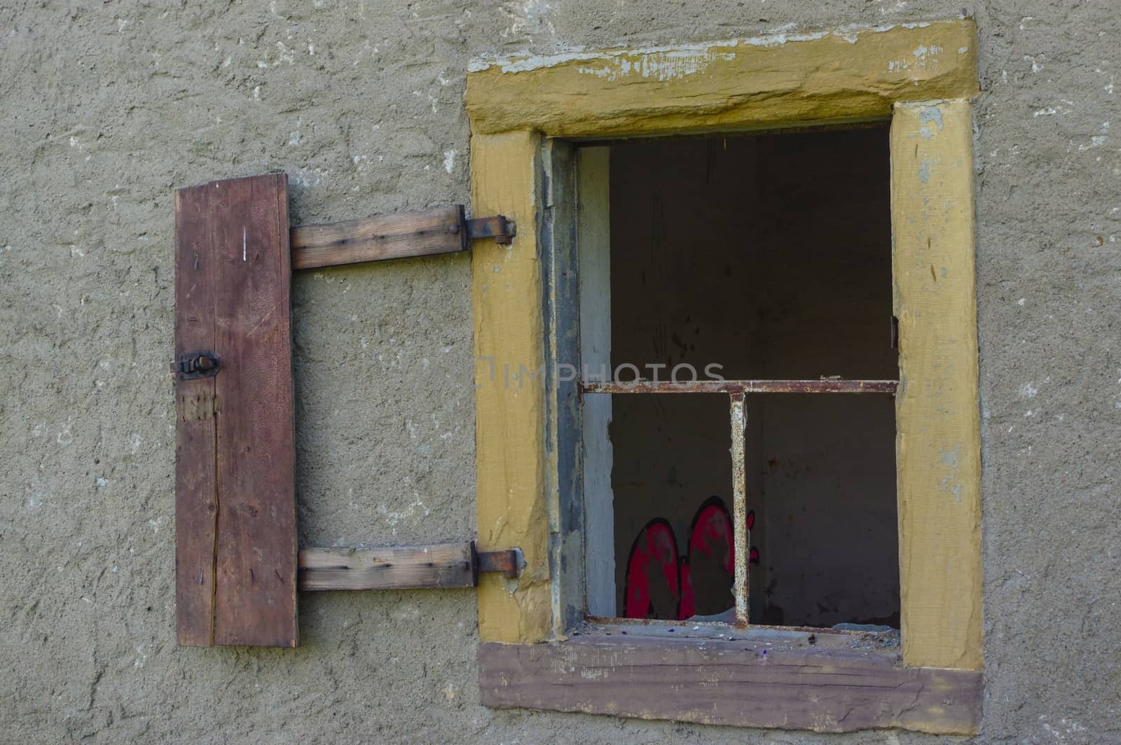 an old open broken window on wall