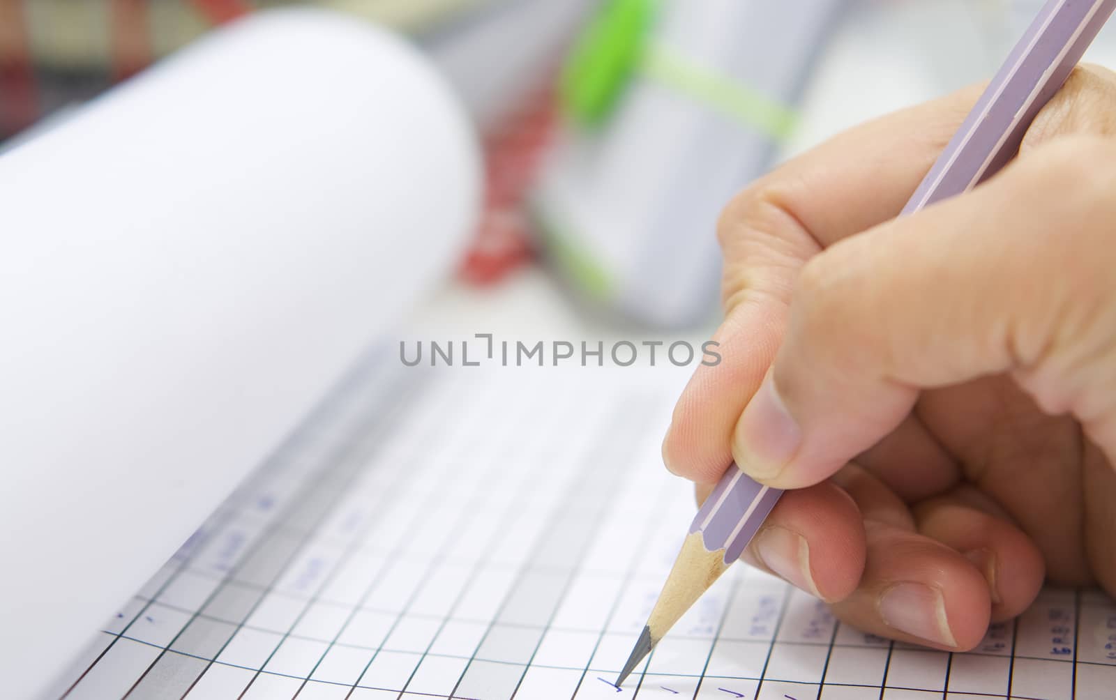 Hand with pencil over checklist form on desk at office.