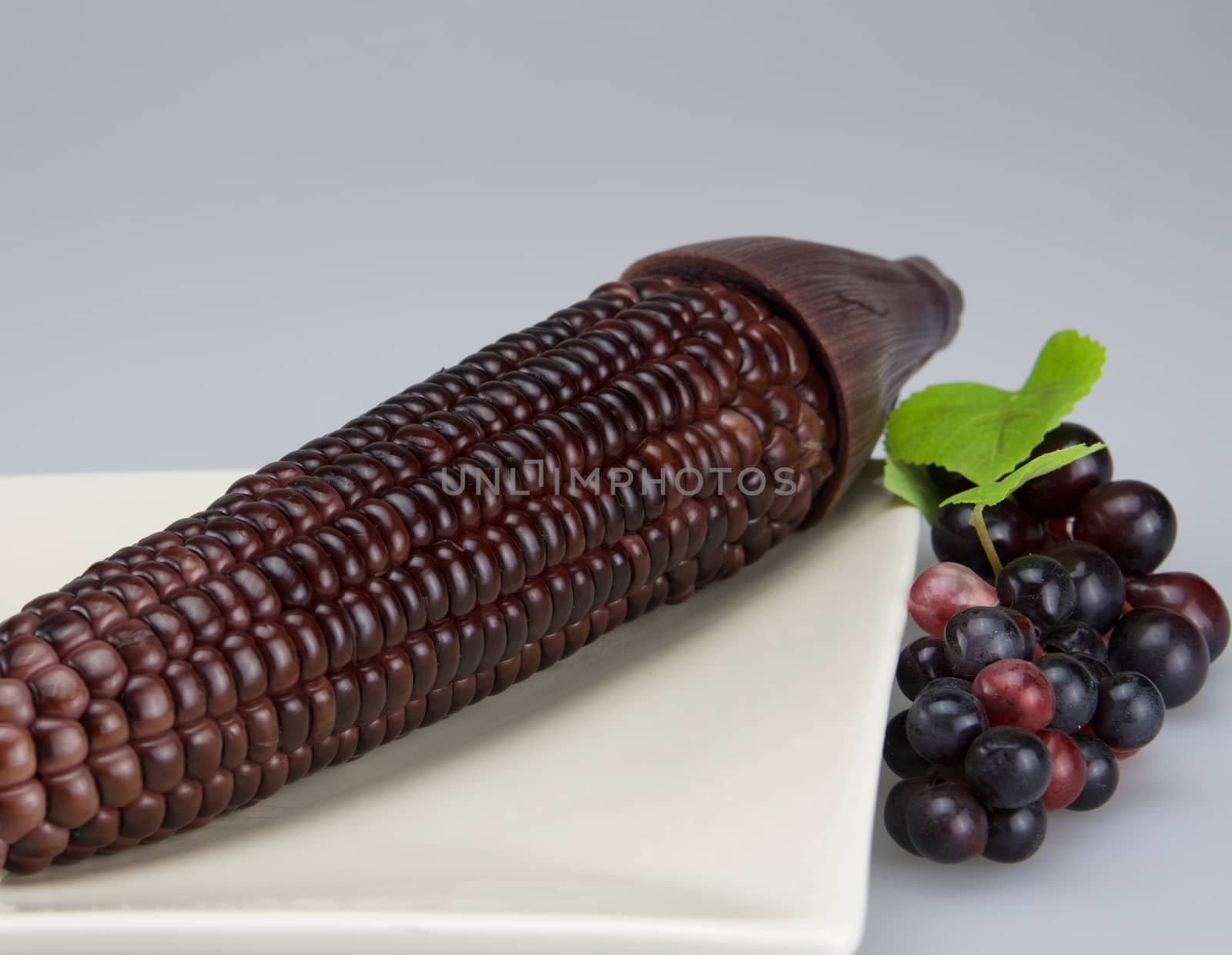 Purple corn put in plate and beside it has some grape.