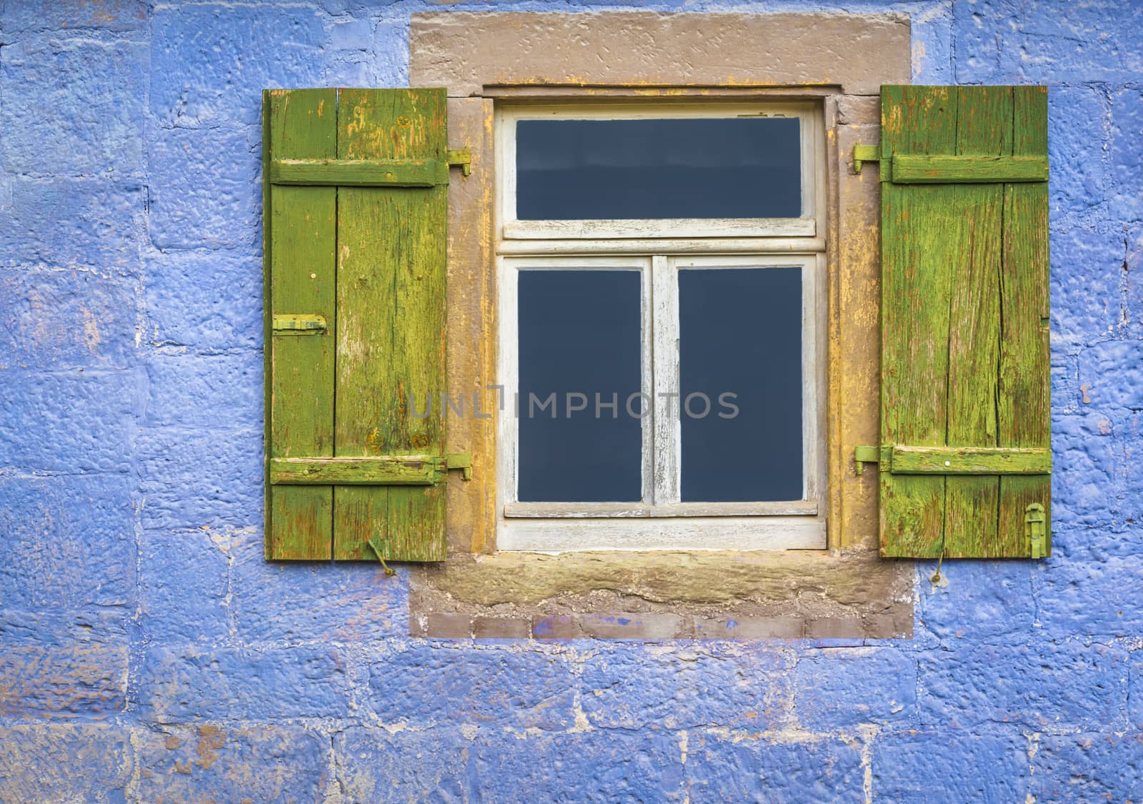 Architectural details over a window with wooden shutters, from an antique german house with walls painted in blue.