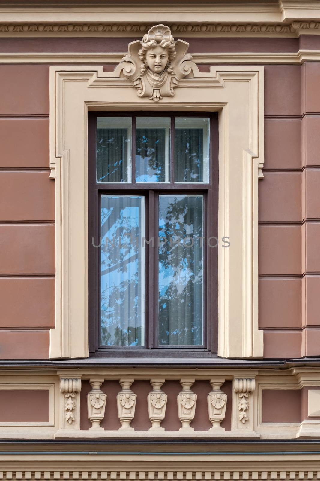 The facade of the building with walls of pink light and a window with a bas-relief. From the series window of Saint-Petersburg.