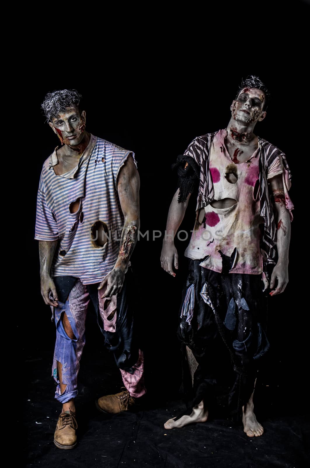 Two male zombies standing on black background walking towards camera