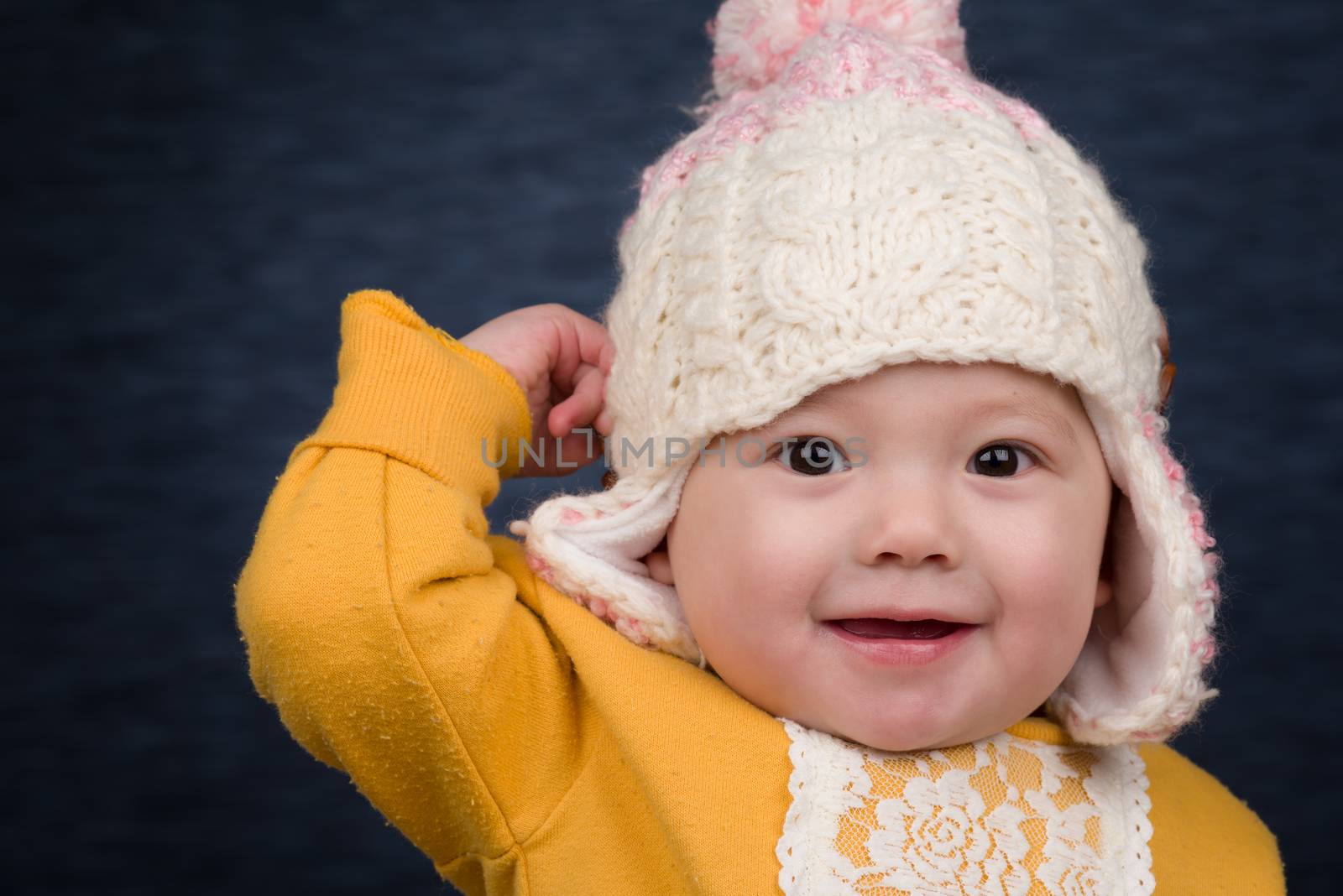 A smiling baby girl wearing a knit winter hat.