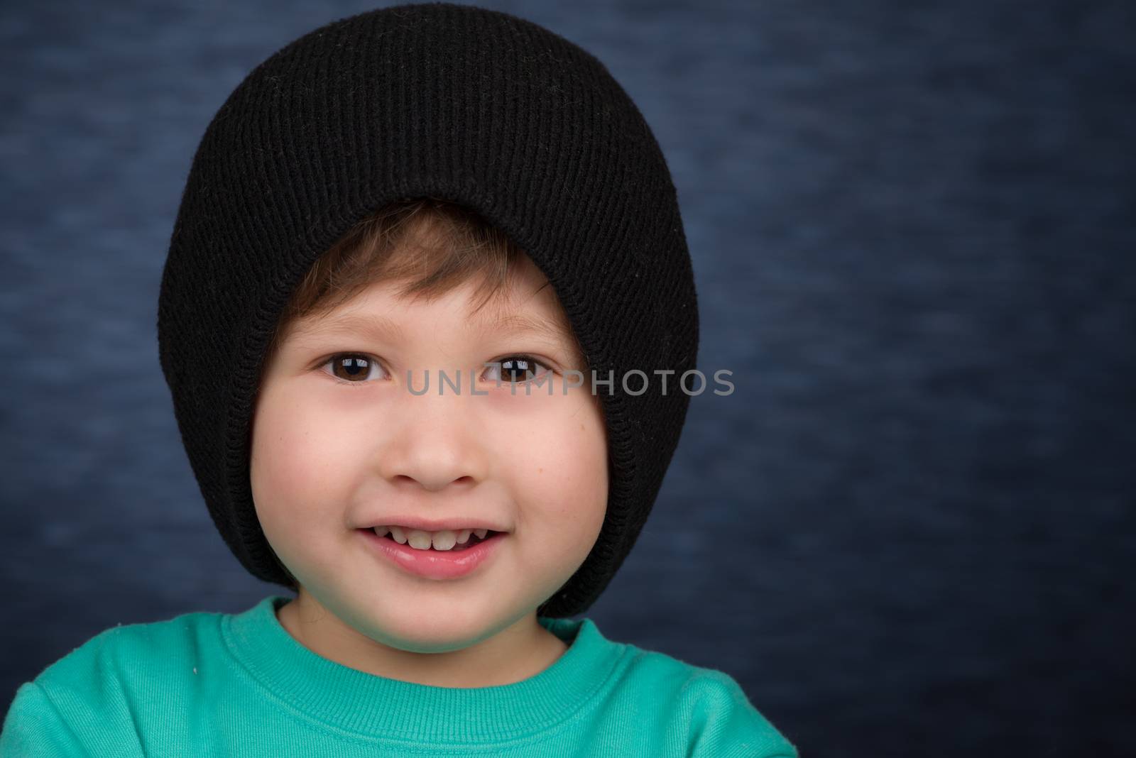 A smiling young boy wearing a knit winter hat.